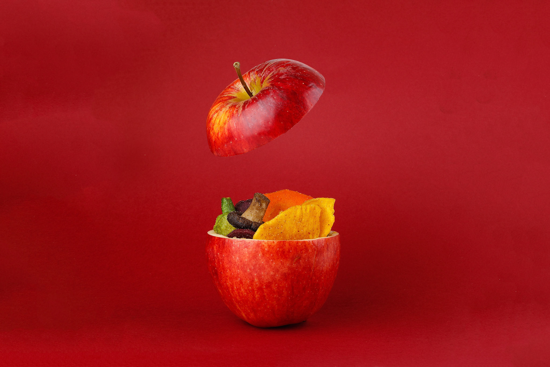 Healthy vegetable chips yellow sweet potato purple sweet potato carrot green radish green beans and shiitake mushrooms in hollow red apple red background