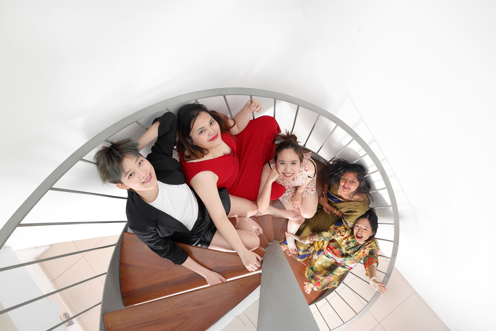 Young southeast asian woman group sitting on indoor spiral staircase happy enjoy fun look fun top view
