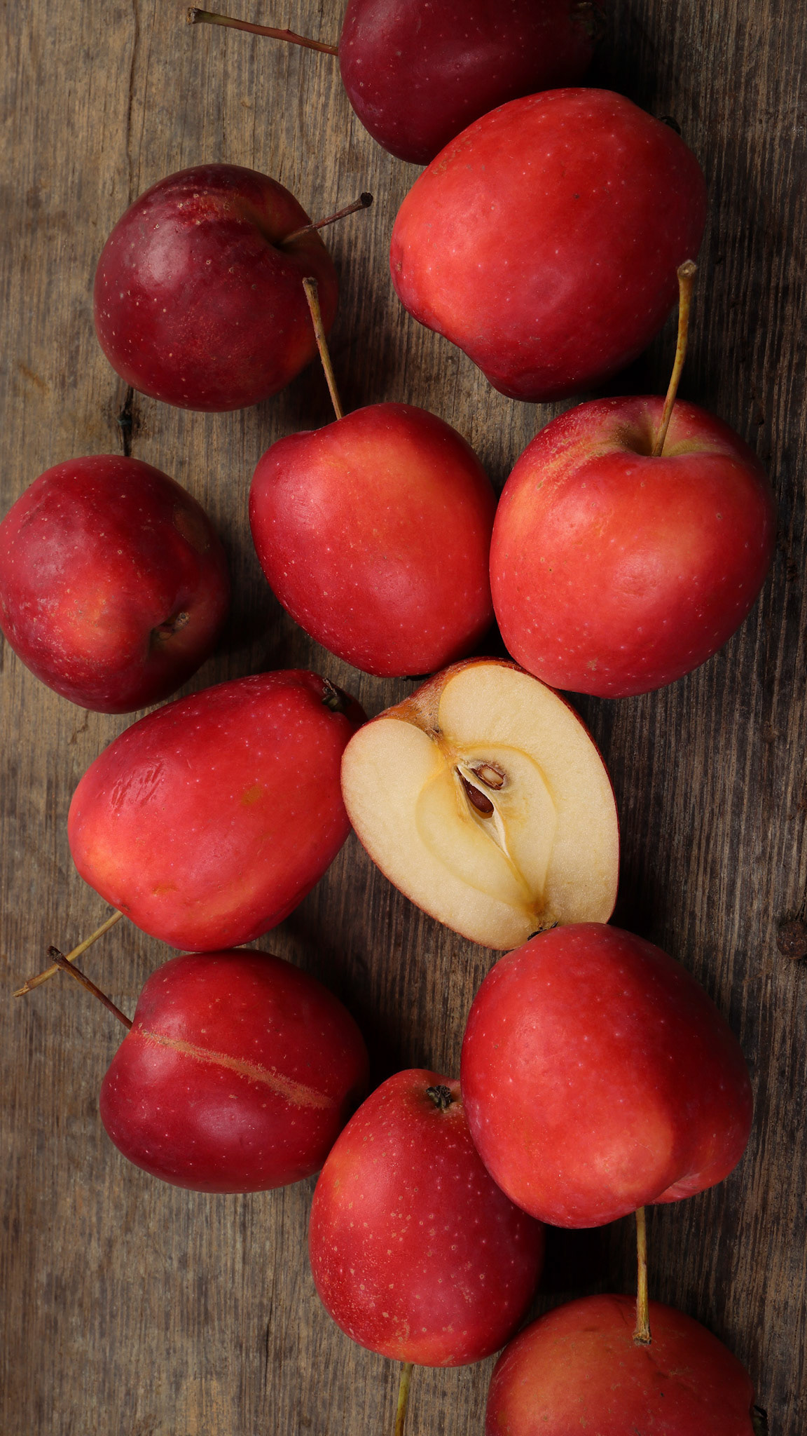 Small red Autumn Strawberry shaped Apple cut slice seed on rustic wooden background