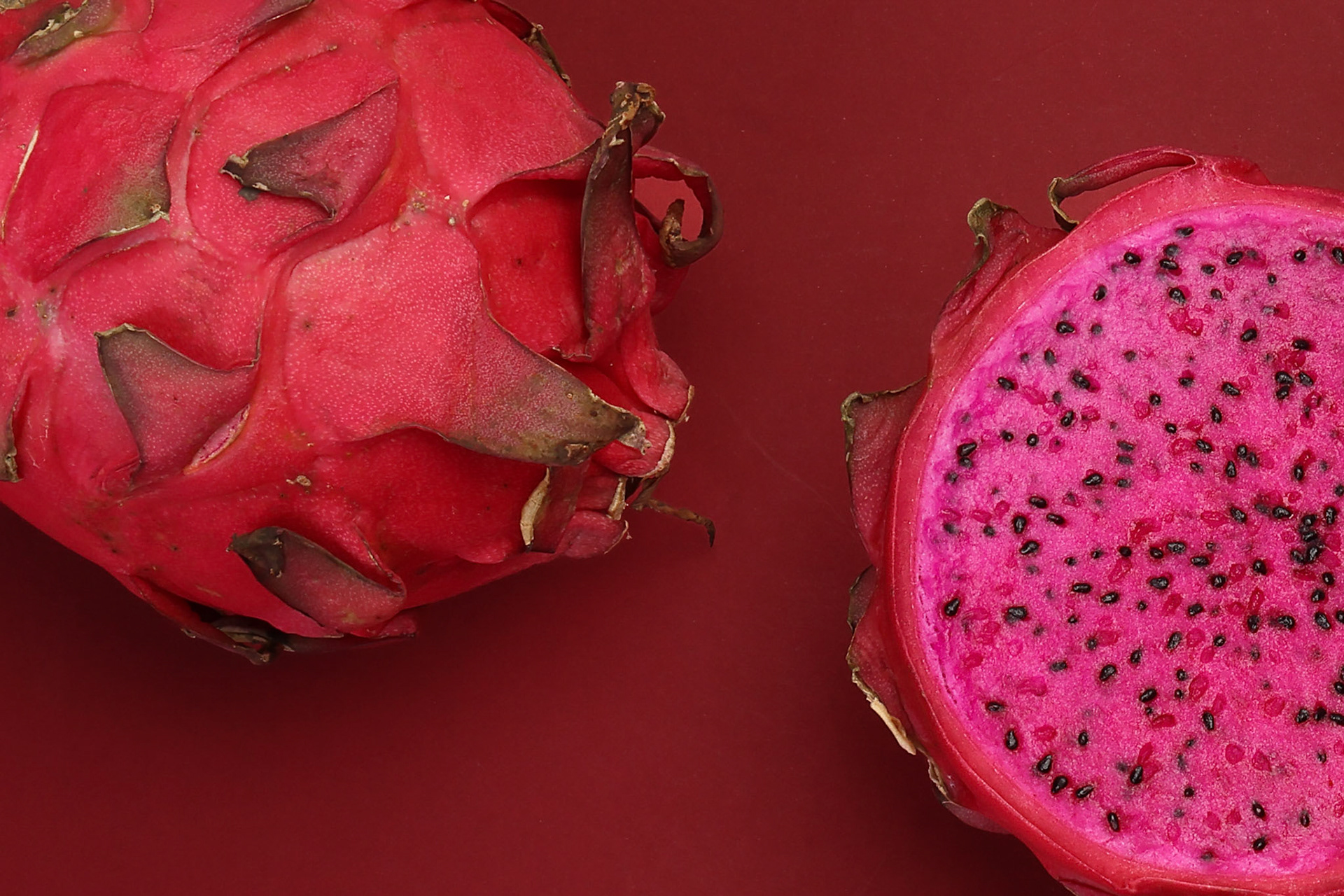 Ruby red exotic cactus dragon fruit whole cut half on red background