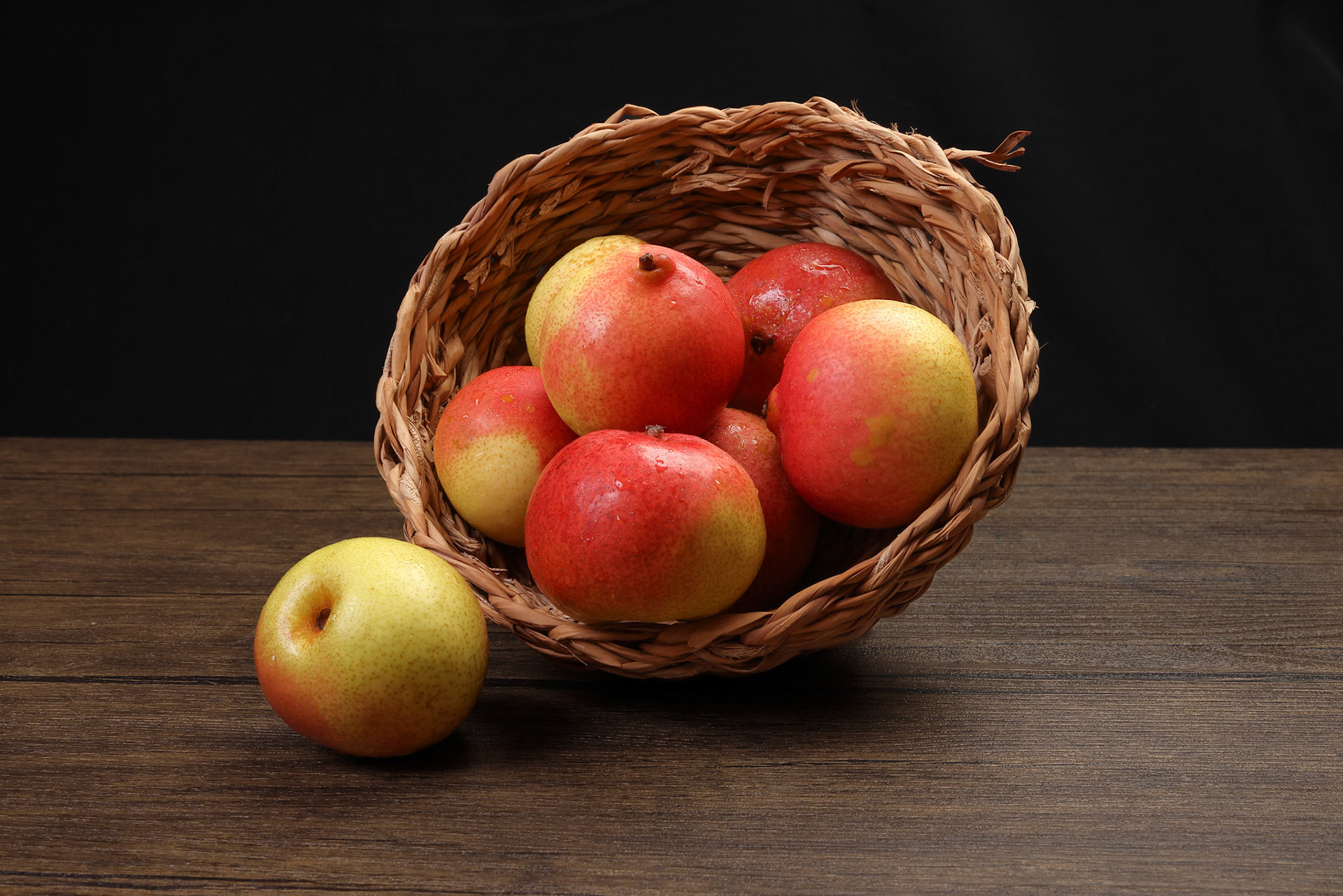 Green yellow red ripe mini pear sweet juicy in basket on wooden table dark background