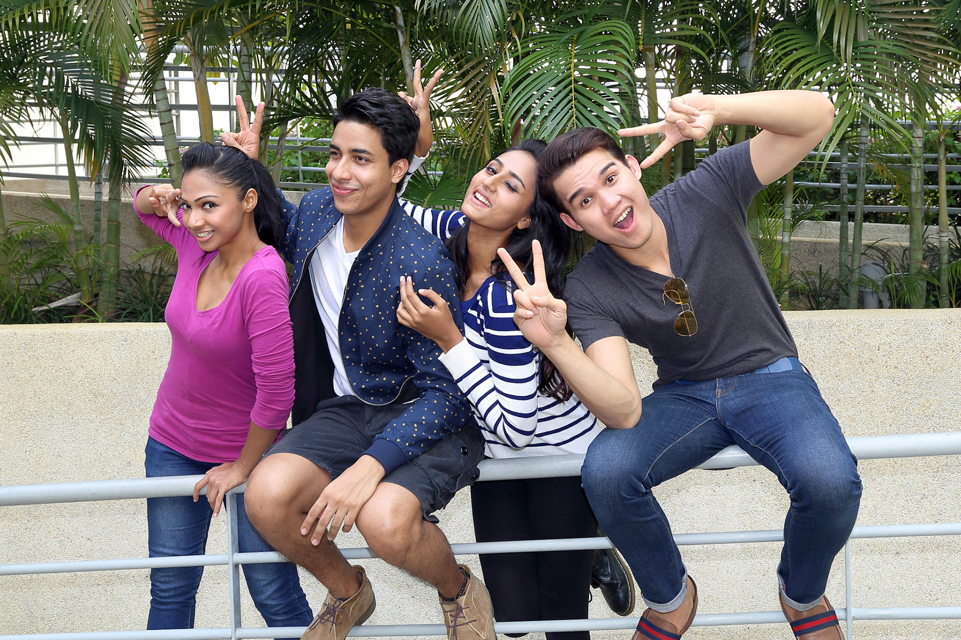 group of Asian young man woman friend student colleagues sting holding swinging on railing happy fun joy