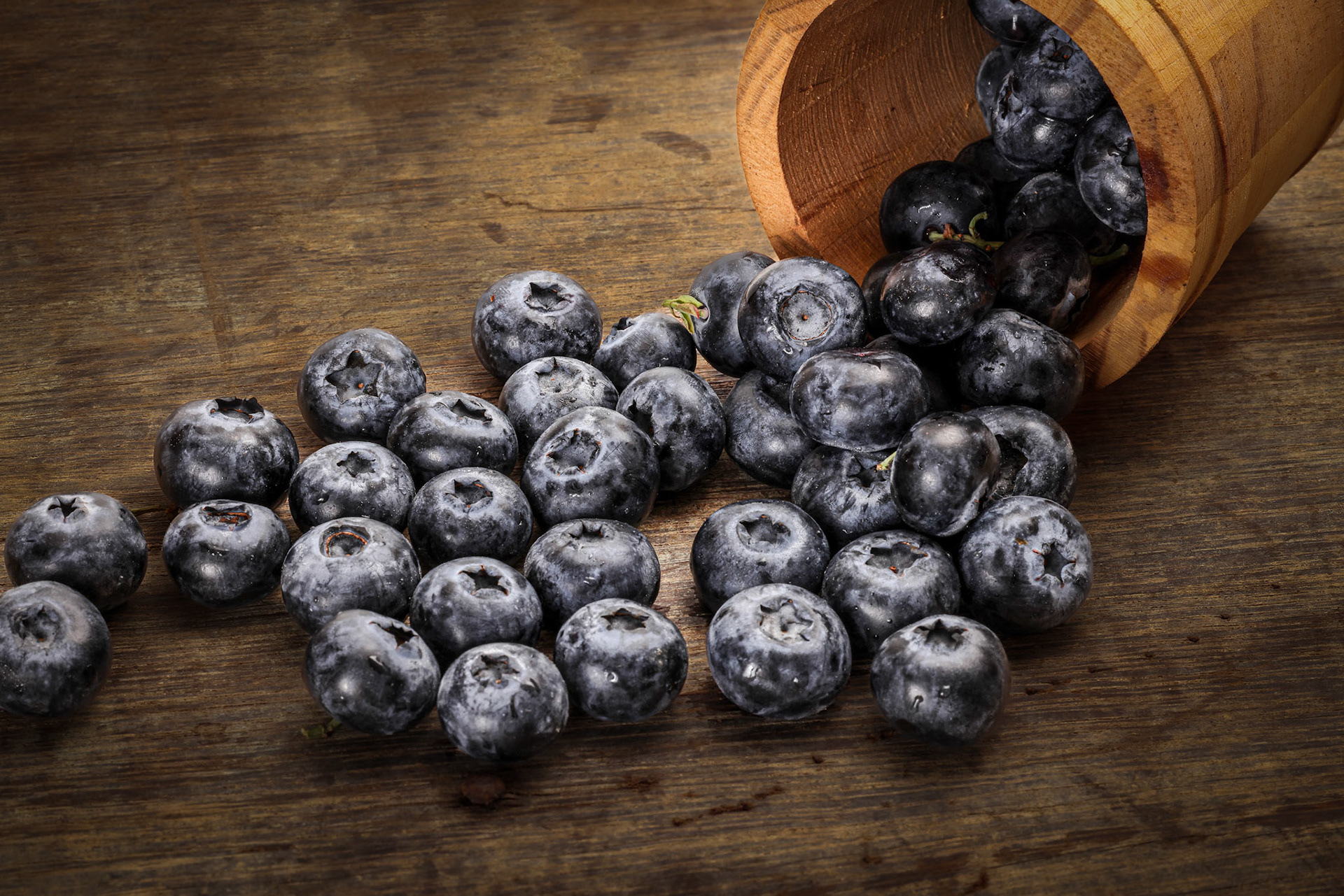 Fresh ripe whole blueberries on rustic wood background mini wooden bucket blue berry