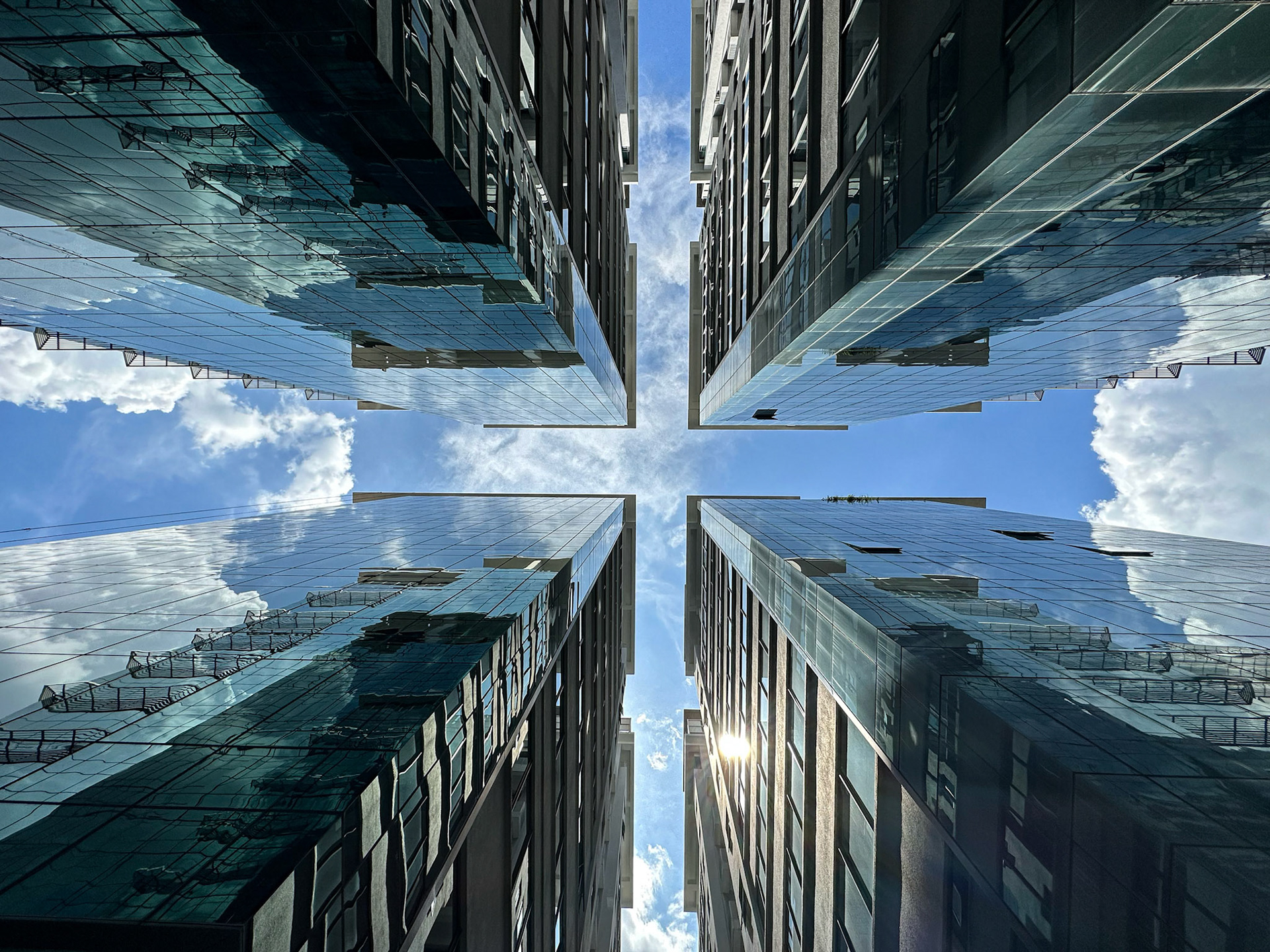 Highrise commercial glass panelled building under clear blue and light cludy sky