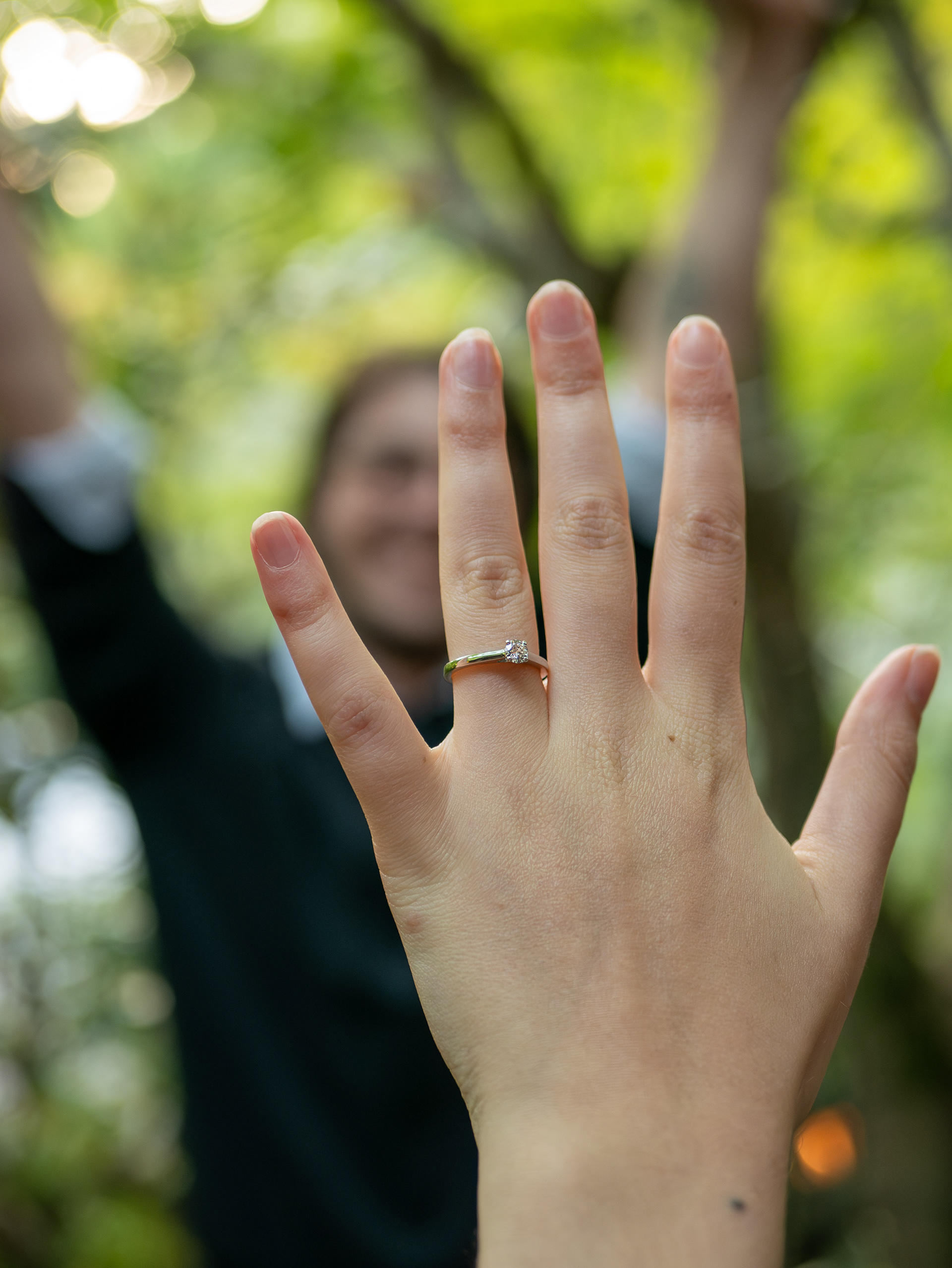 Bride showing engagement ring with groom celebrating in the background during a surprise proposal in Kyoto, captured by Paren Creates.