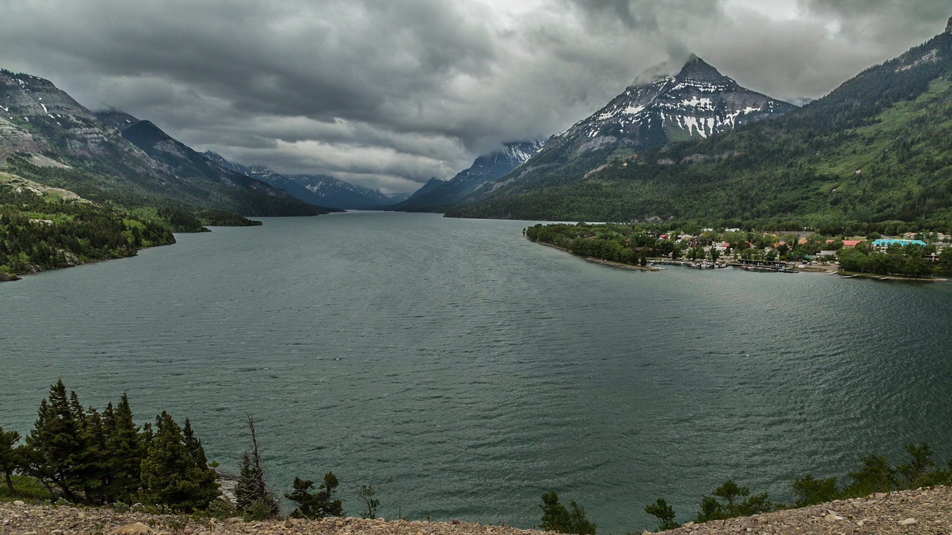 Waterton is really a pretty small town that sets on some flat land beside Upper Waterton Lake. The businesses and homes are at the right side of this image.  From this perspective, the view probably has not changed a lot since the early 1900s, when the hotel was build.  I suspect the glaciers on the mountains are smaller.