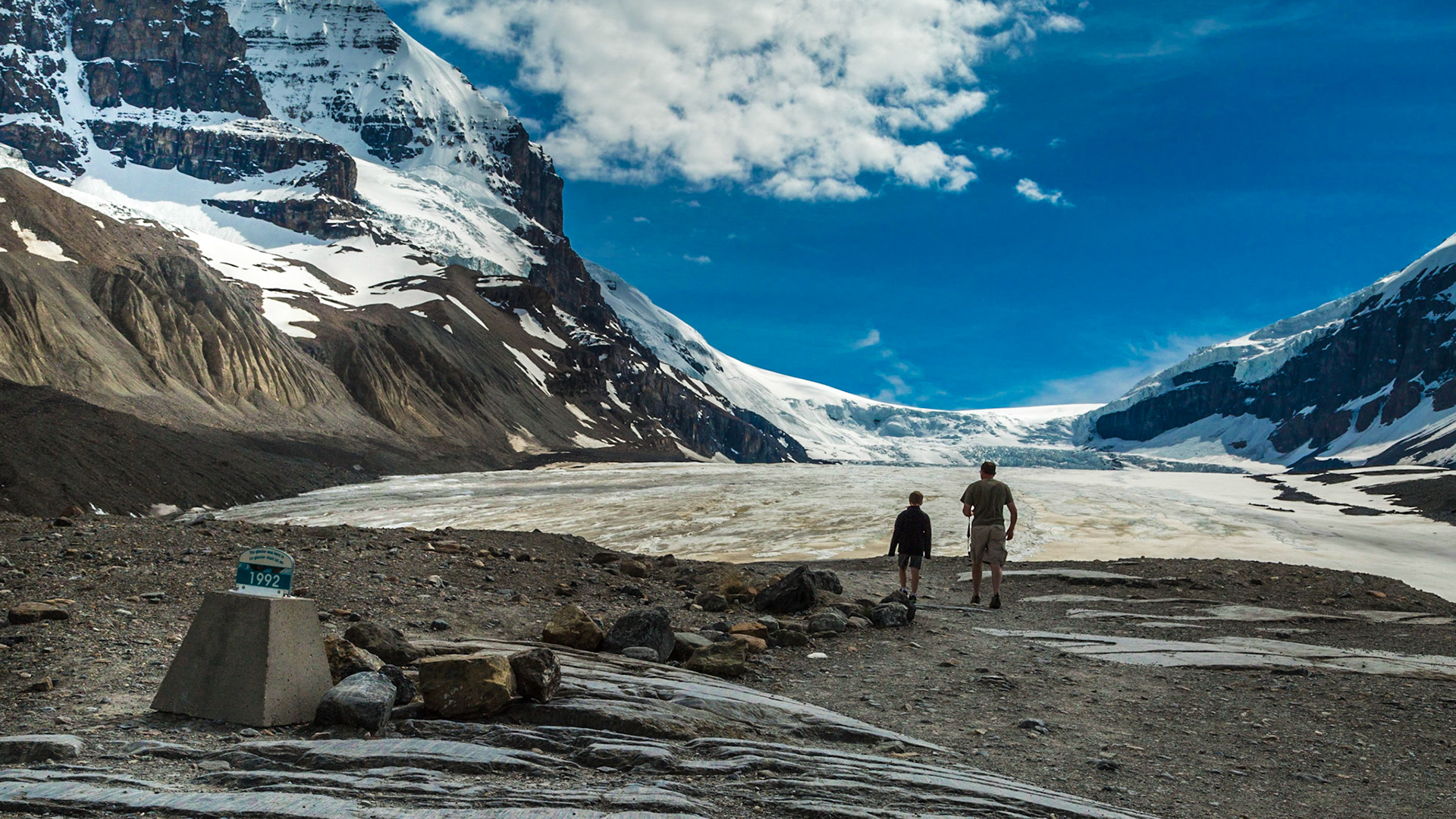 Approaching the glacier, a father and son passed the 1992 marker for the edge, eager to see it.  Their silhouette created an interesting view.  There were several similar markers along the trail, beginning near the parking lot.  As I remember, they were all after the mid-1900s.