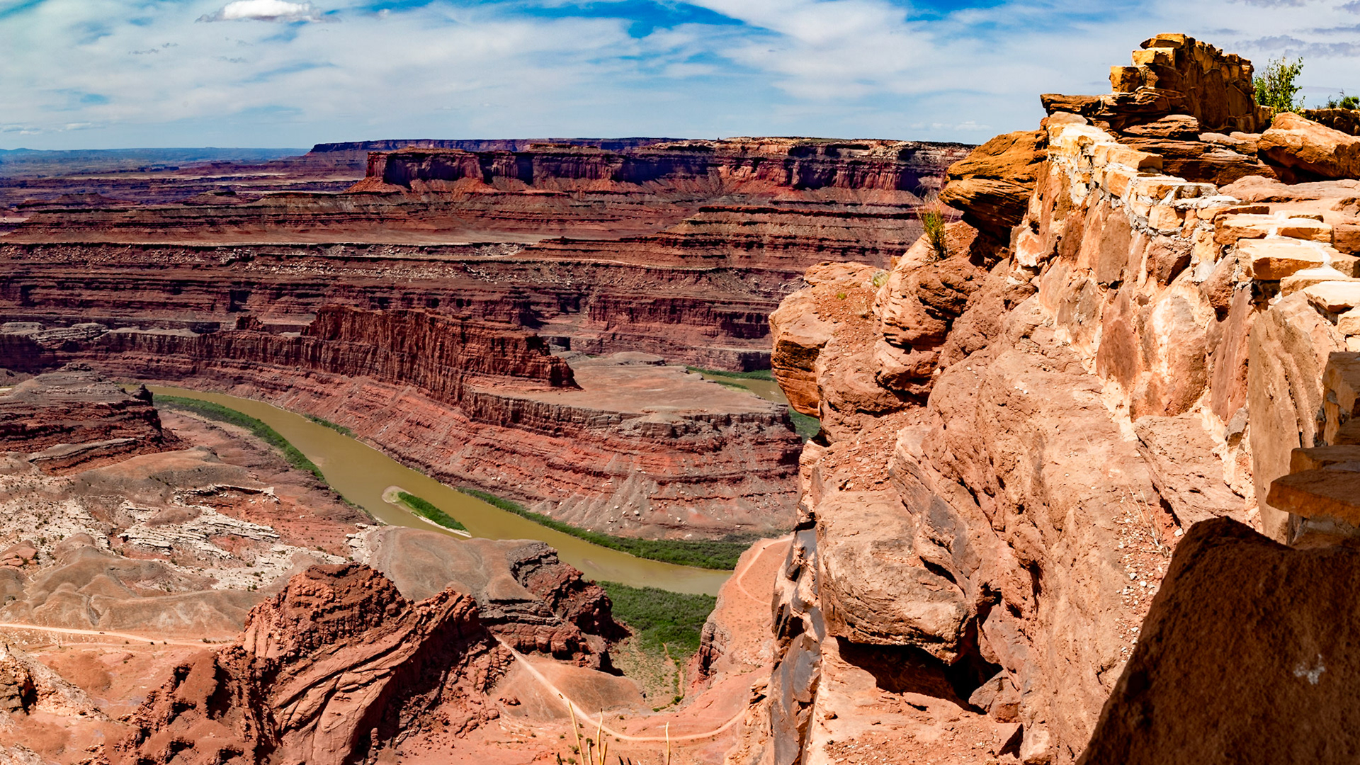 To get an idea of the scale, notice that there are two cars on the road at the bottom of the foreground cliff. One is yellow.  The other has reds.  From that level, there is another cliff rim high above the river.