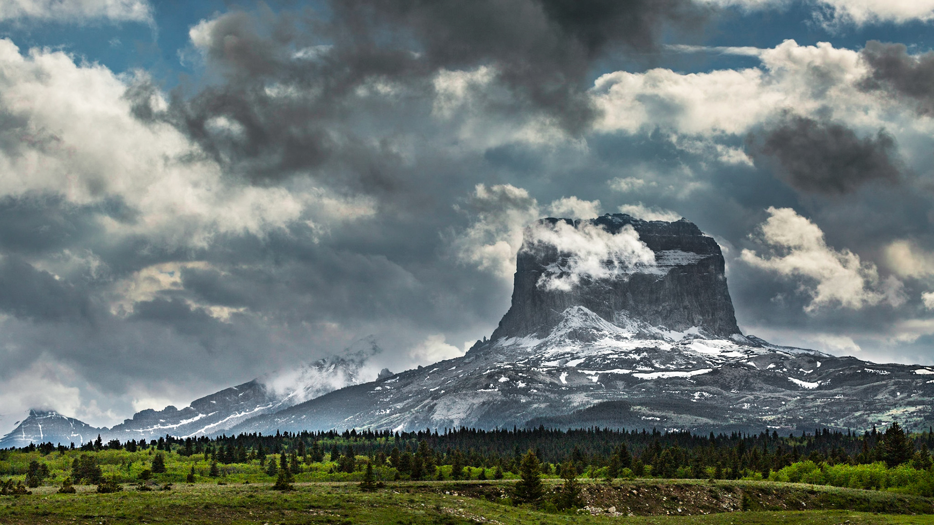 I remembered Chief Mountain from the 2001 trip through this area and looked forward to seeing it again. In my memory, it was dramatic. The formation was “socked in” with clouds when we first saw where it was. We waited a good while at the first opportunity to stop. Behind the mountain from us, the sky seemed relatively clear. The wind seemed to be blowing the clouds away. In a while, I realized that the wind parting around the mountain was probably causing the clouds on our side. We moved on. After a few miles, we found a viewing area that gave me this image.