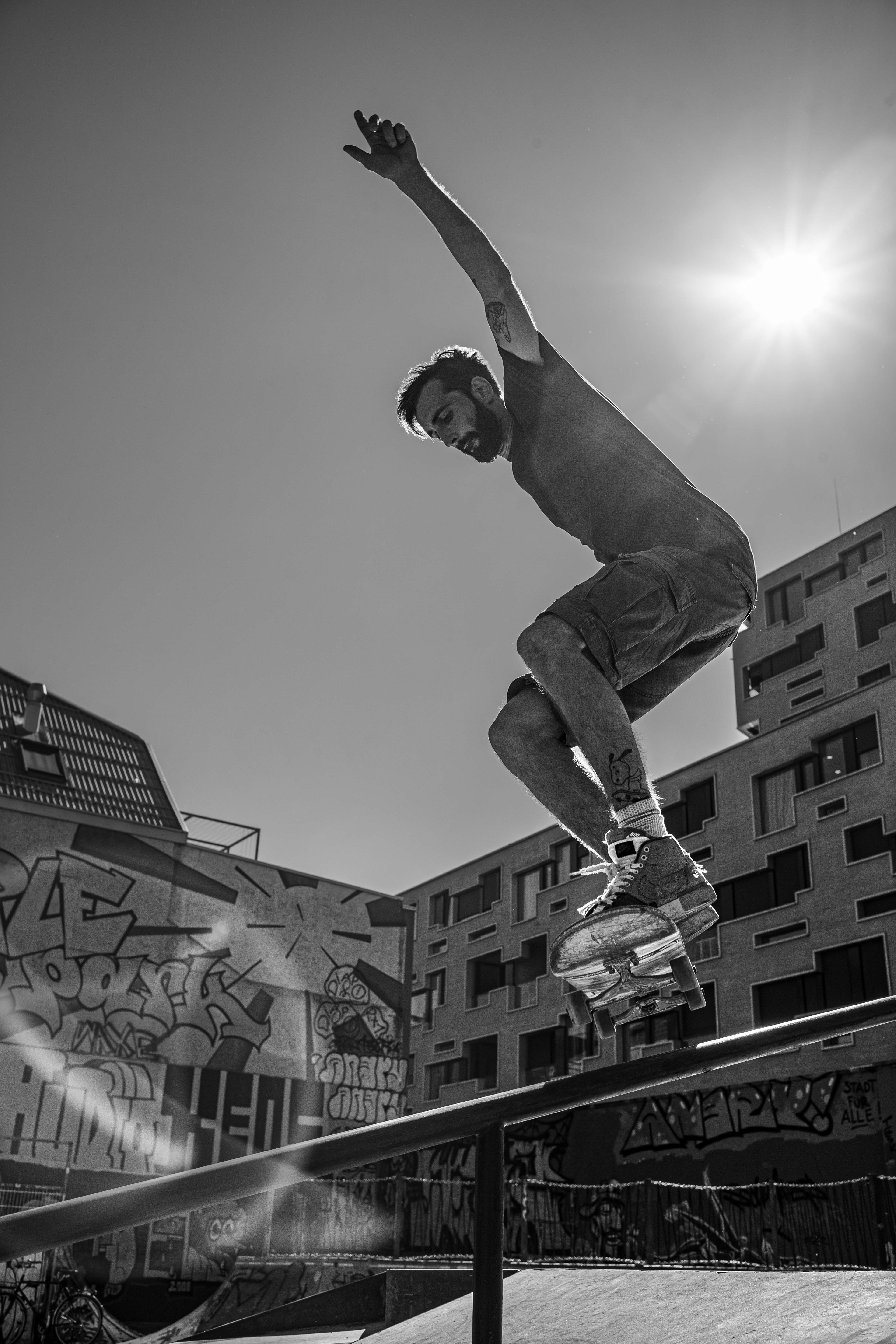 A dynamic, razor-sharp shot of a skateboarder in intense body tension mid-air at Purple Park Basel, backlit by the blazing sun. Photography by Carmine Castelli.