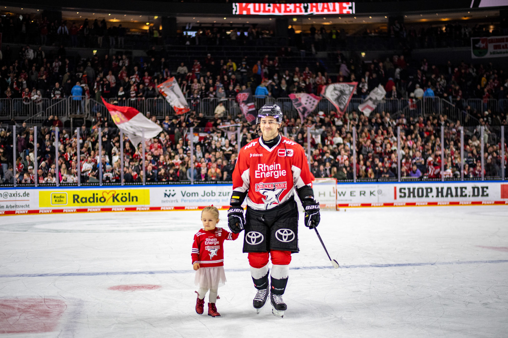 Nicholas Bailen mit seiner Tochter nach dem Sieg auf dem Eis; DEL Kölner Haie - Fishtown Pinguins Bremerhaven, 30.01.2024