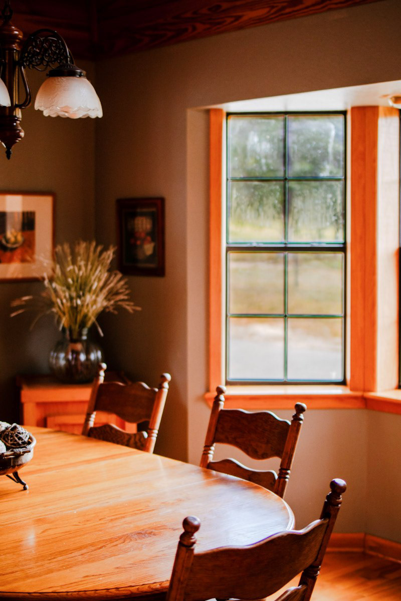 Warm wood tones and plenty of natural light set the perfect scene for gathering around the table. Moody, lodge-inspired interiors make this dining space feel both modern and traditionally inviting. Space highlighted by Arkansas Air BnB photographer.
