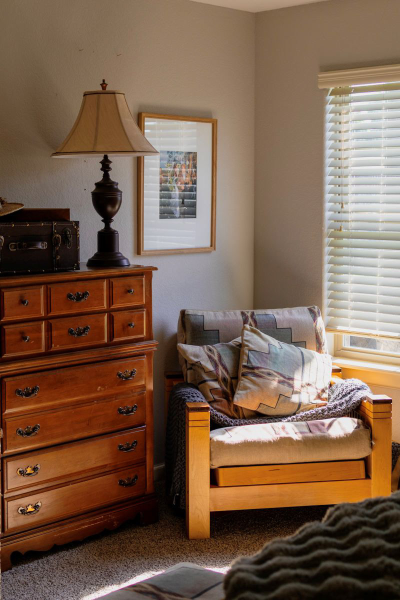 Thoughtful details and vintage-inspired corners. A sunlit reading nook styled with earthy tones, natural wood furniture, and cozy textures to make guests feel right at home. Botique vacation rental captured by Arkansas Air bnb photographre.