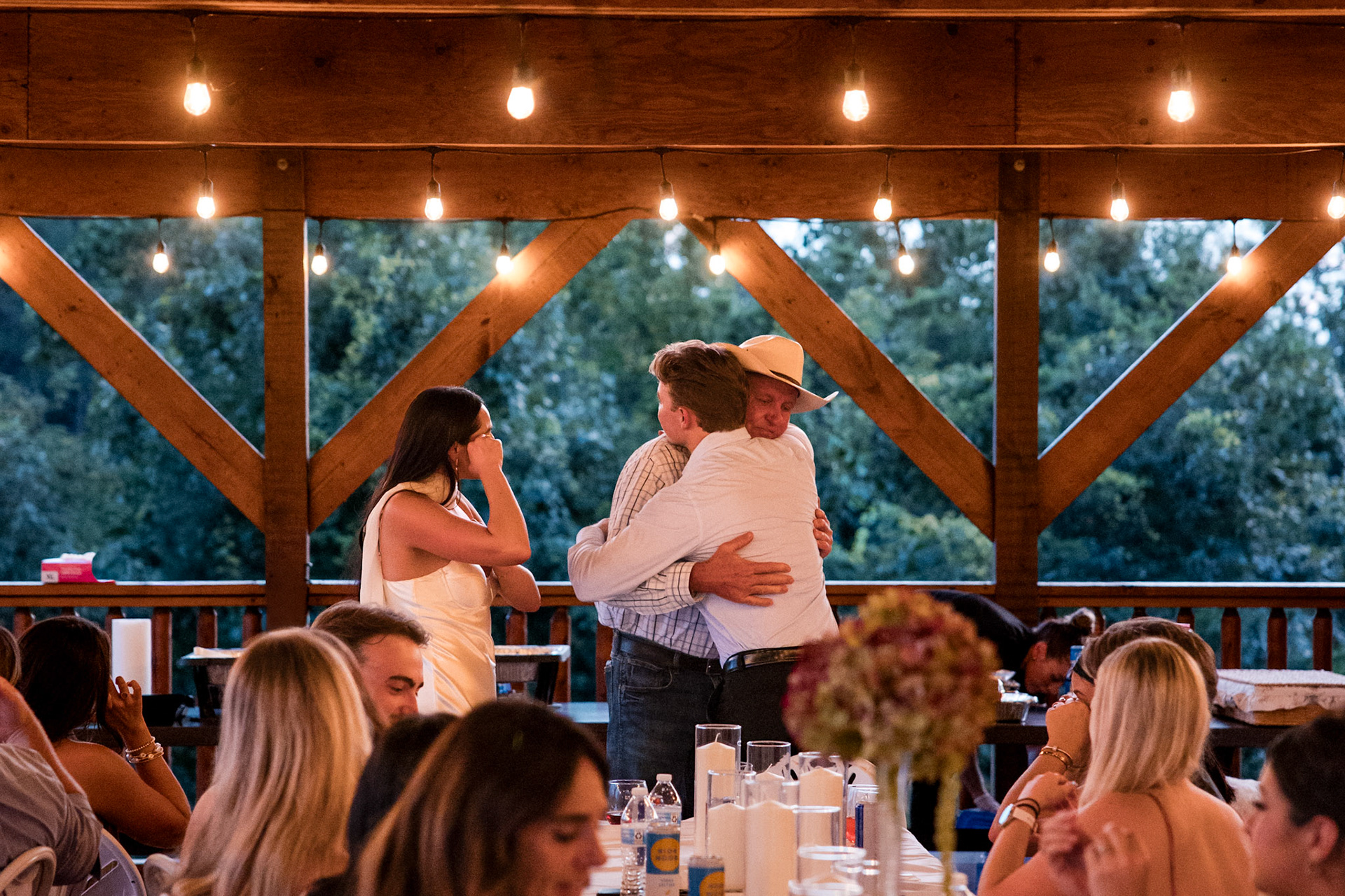 	Candid moments capturing the love and excitement at a rustic Sevierville, TN rehearsal dinner under romantic string lights. Professional wedding event photography.