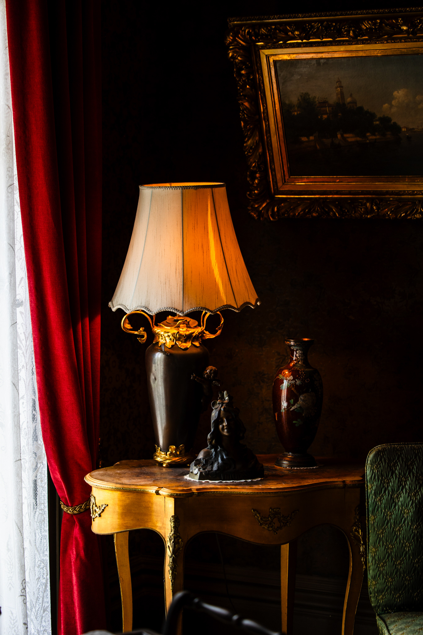 Detail view of a round table with crystal dishes and lamp light against red velvet curtains at the Mallory-Neely House, Memphis