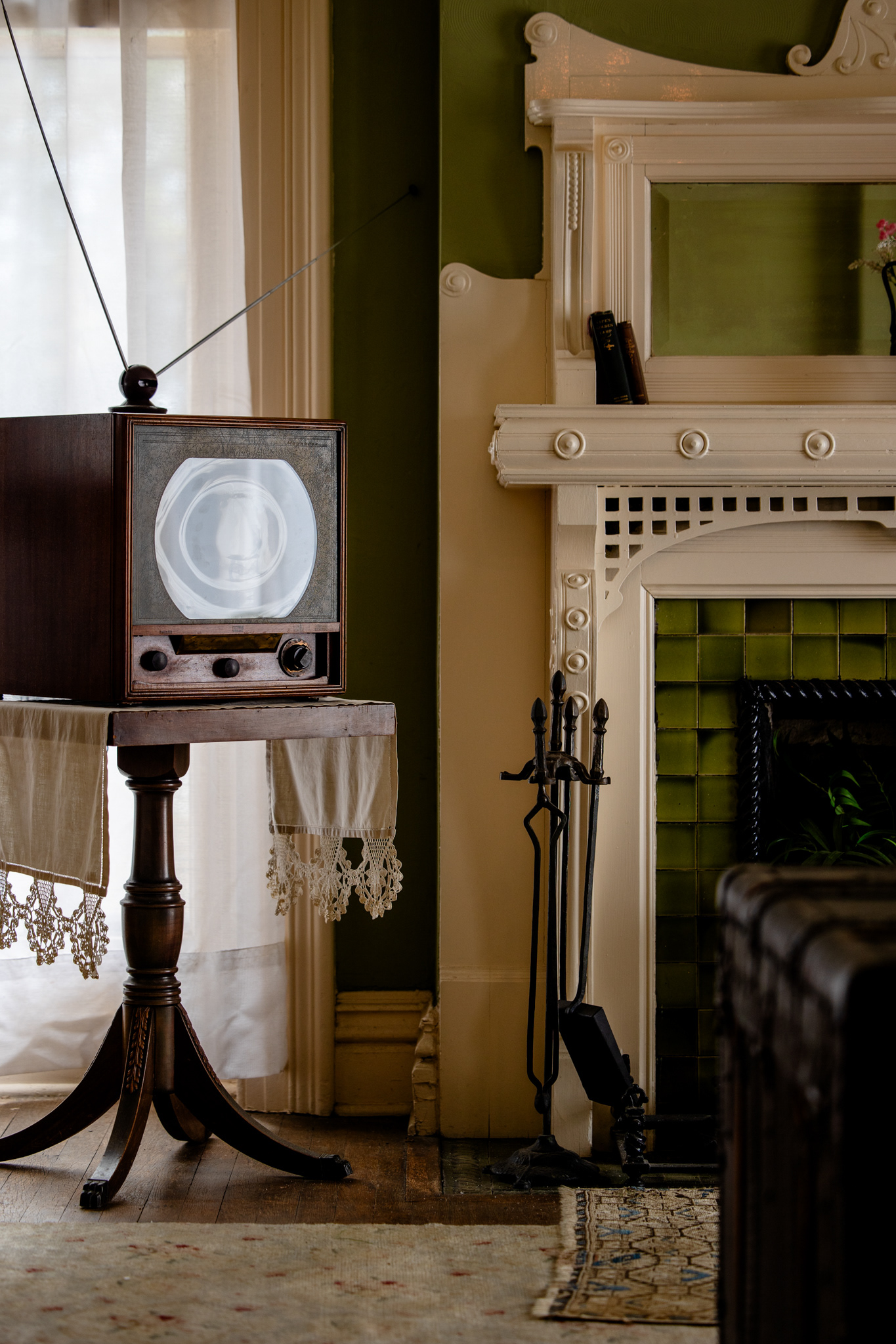 Vintage television set on a marble-top stand beside a green tiled fireplace at the Mallory-Neely House, Memphis