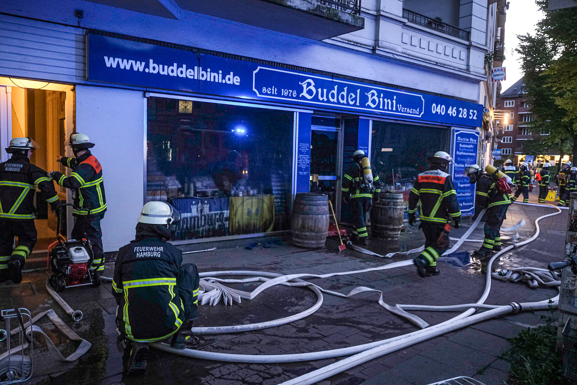 Als die Einsatzkräfte der Feuerwehr Hamburg am Sonntagabend um 21.43 Uhr in der Barmbeker Straße eintrafen, schlugen die Flammen bereits aus den Fenstern der Rückseite eines fünfstöckigen Wohn-und Geschäftshauses. Aus noch ungeklärter Ursache brach in Winterhude bei "Buddel Bini", einem Ladengeschäft für Hamburg-Souvenirs, ein Brand aus. Anrufer hatten zunächst gemeldet, dass das Feuer in einer Erdgeschoss-Wohnung ausgebrochen sein soll und Bewohner versucht haben, durch das verrauchte Treppenhaus nach draußen zu kommen. Die Einsatzkräfte konnten den Brand, der offenbar in einem Hinterzimmer des Ladens ausgebrochen war, mit zwei C-Rohren schnell in den Griff bekommen, sodass ein Übergreifen der Flammen auf die angrenzenden Wohnungen verhindert werden konnte. Nachdem das Feuer in dem Laden unter Kontrolle war, wurden alle Wohnungen überprüft. Nach dem erfolgreichen Löschen musste das Treppenhaus belüftet werden. Die Nachlöscharbeiten dauerten noch bis in den späten Abend an. Die Barmbeker Straße wurde während des Einsatzes zwischen Winterhuder Marktplatz und Maria-Louisen-Straße gesperrt.