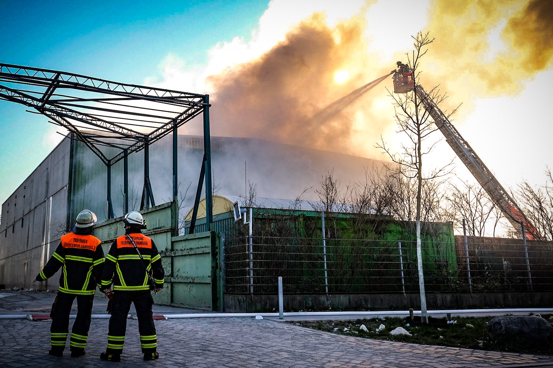 Am Mittwochnachmittag wurde die Feuerwehr Hamburg zu einem Großbrand in die Liebigstraße im Stadtteil Billbrook gerufen. Aus noch ungeklärter Ursache ist dort in einem Gewerbegebiet eine 40 mal 60 Meter große Lagerhalle, in der Verpackungsmaterialien gelagert werden, in Flammen aufgegangen. „Wir haben hier einen Großeinsatz. Das Feuer entspricht der Stufe drei. Mittlerweile sind rund 80 Kameradinnen und Kameraden am Einsatzort und versuchen das Feuer in der Lagerhalle zu löschen“, so ein Feuerwehrsprecher. Die Flammen haben das Dach bereits komplett zerstört. Ein Problem sei aktuell jedoch der hohe Wasserverbrauch. Es mussten 100 Meter lange Schlauchleitungen gelegt werden. Verletzte gibt es bisher keine. Die Flammen haben etwa ein Drittel der Halle erfasst und seien durch das Dach gebrochen. Wegen der starken Rauchentwicklung gab die Feuerwehr Hamburg eine Warnung an Anwohner heraus. Die Rauchsäule ist mehrere Kilometer weit bis nach Tonndorf zu sehen. Derzeit versucht die Feuerwehr Hamburg den Brand unter Kontrolle zu bringen.