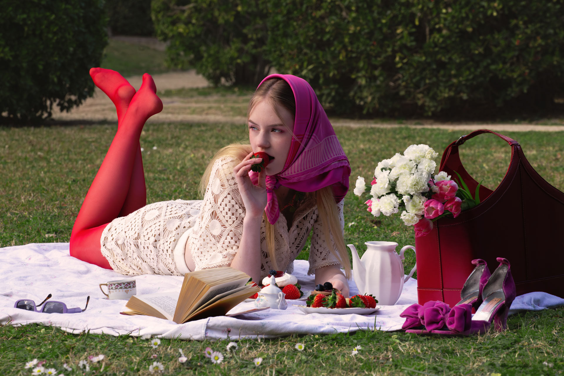 Model on a picnic blanket in red tights and a pink headscarf, Spring Charm, photographed by Alberto Branca