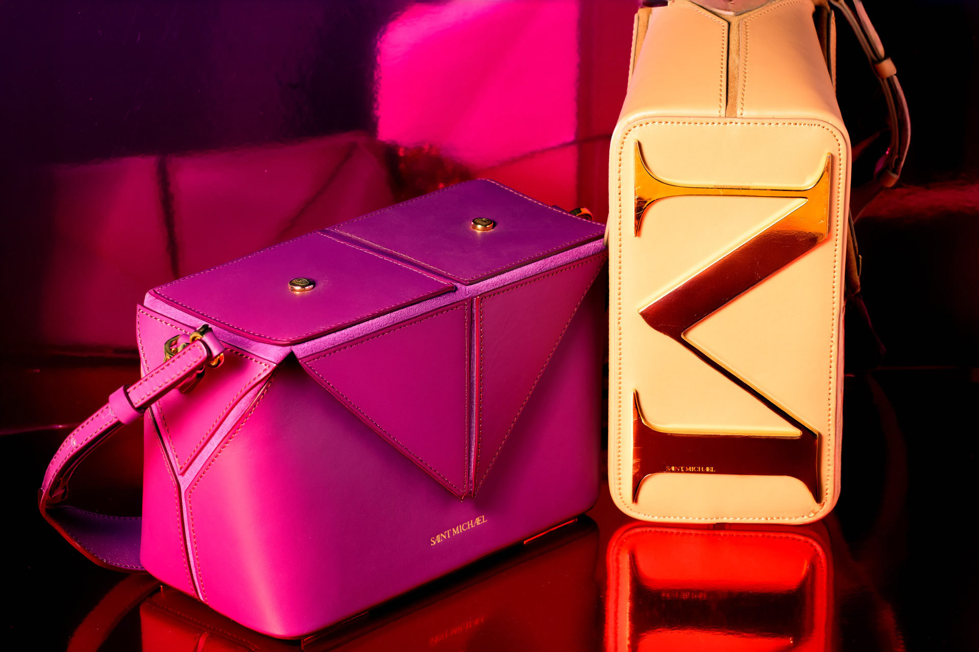 Two Saint Michael bags, magenta geometric crossbody and cream bag with gold hardware, photographed by Alberto Branca
