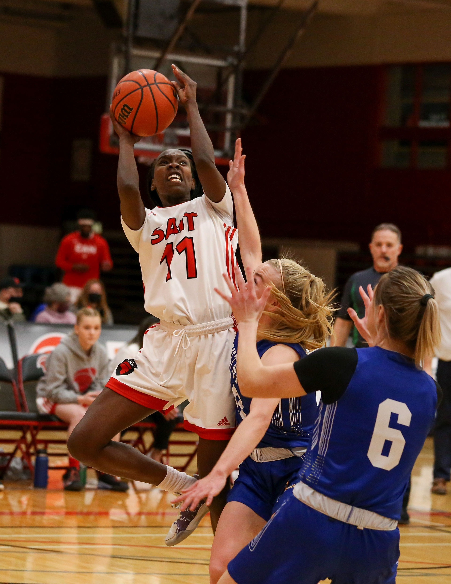 SAIT Trojans forward Anegor Wol takes a shot at the basket, while a member of the Lightning tries to stop her at SAIT’s Campus Centre gym in Calgary on Saturday, Feb. 26, 2022.