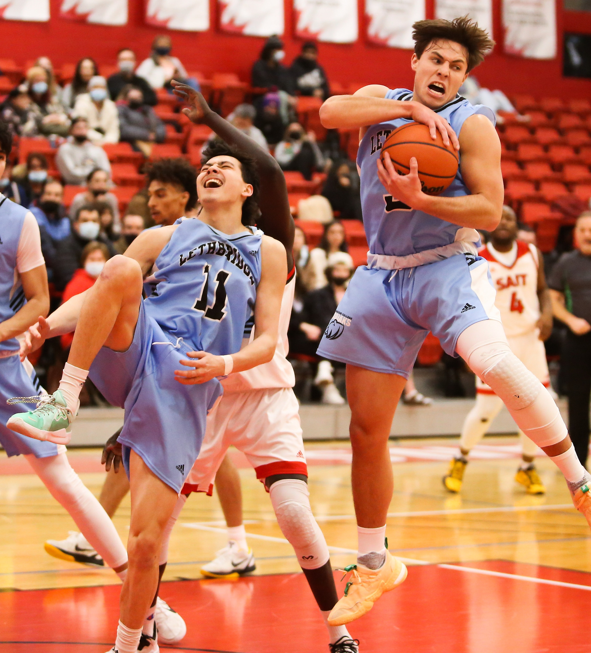 Kodiaks guard Ty Lewis grabs the ball, while his teammate guard Tomoya Owens grabs his ankle in pain at SAIT’s Campus Centre gym in Calgary on Saturday, Feb. 19, 2022. The Trojans defeated the Kodiaks 69-68 during Alberta Colleges Athletic Conference regular season play.