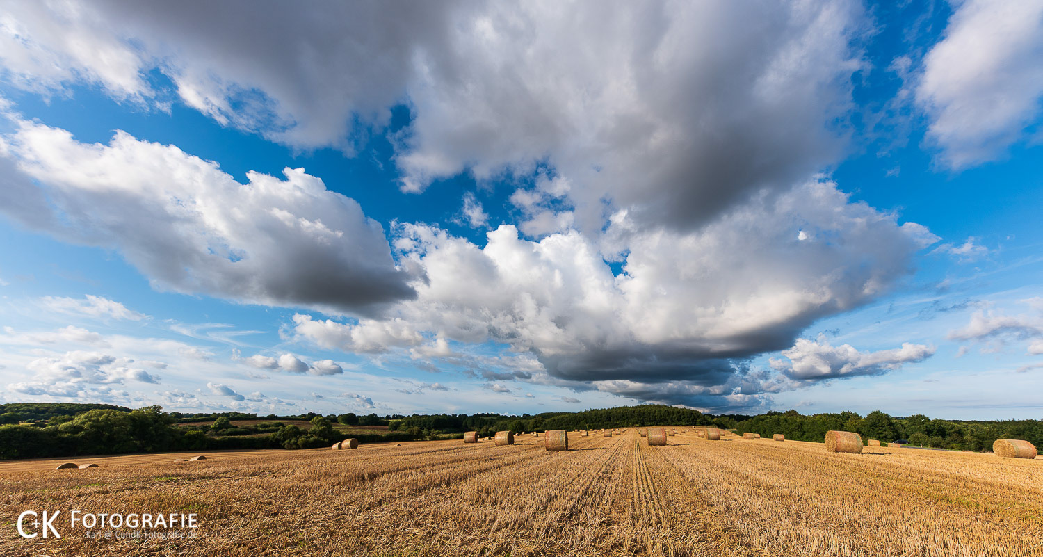 Wolken über Stoppelfeld mit Strohballen
