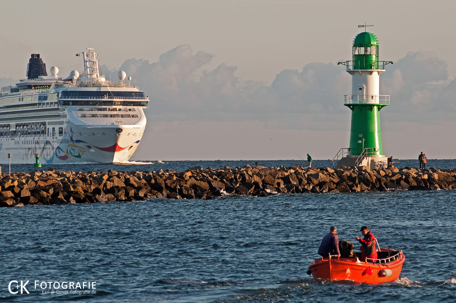 Kreuzfahrtschiff Norwegian Star und Fischerboot vor dem Molenleuchtturm in Warnemünde