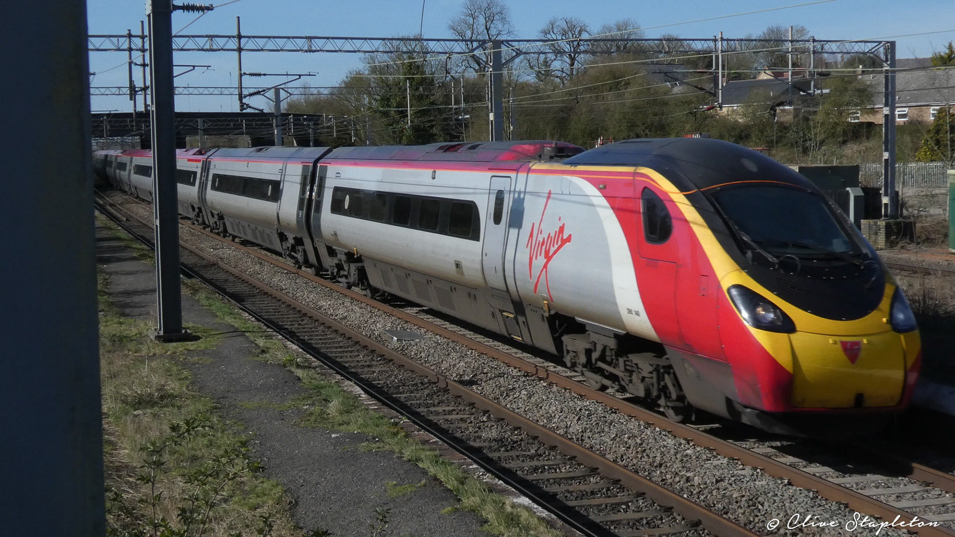 A class 390 heads through Castlethorpe Station towards London