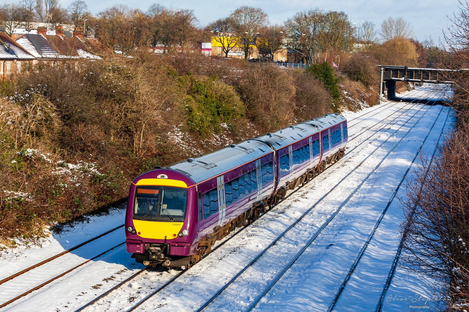 A Class 170 in EMR Livery approaches Derby on a snowy day in January 2021 with a train from Stoke on Trent