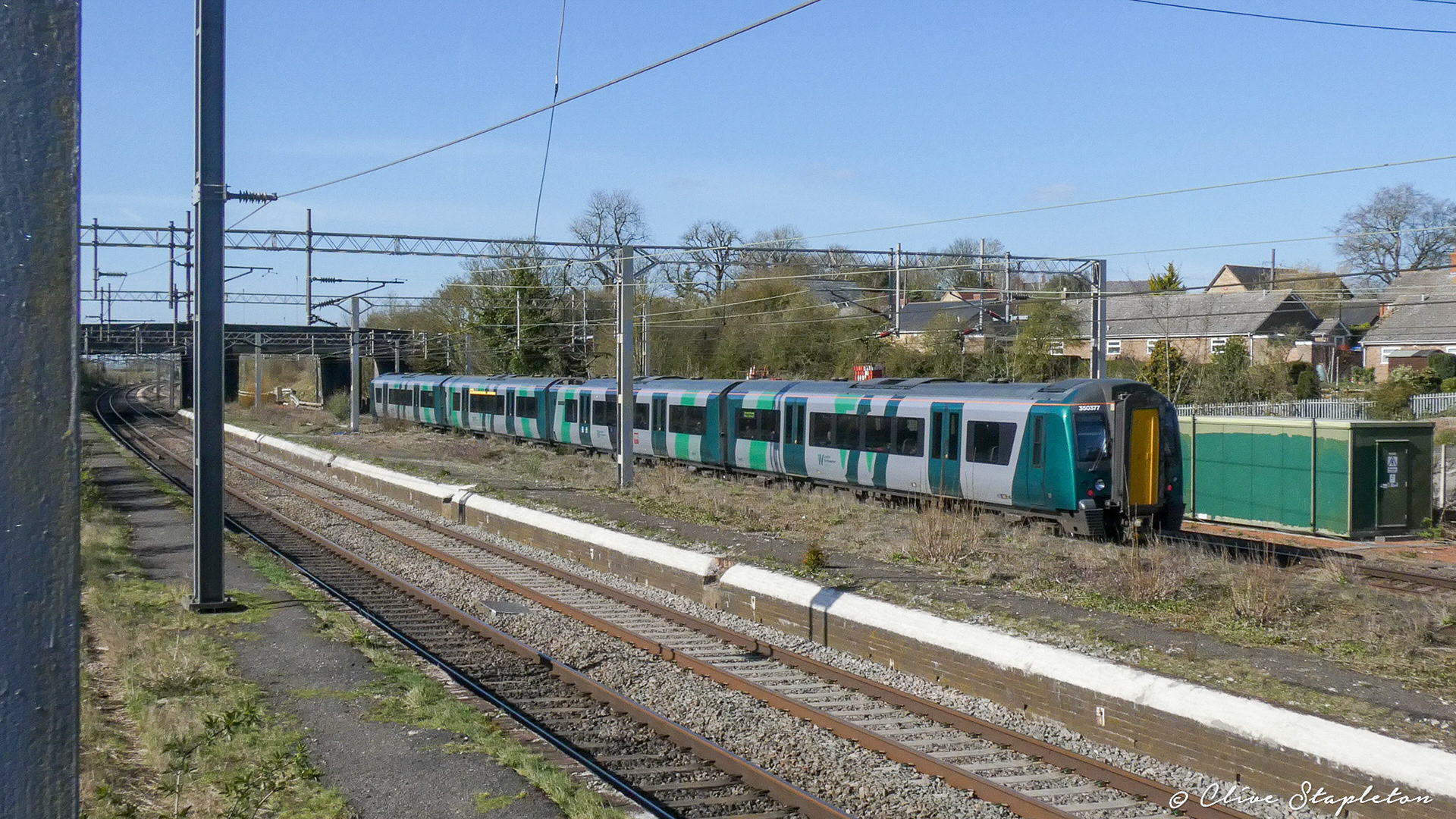 A class 350 Desiro heads through Castlethorpe Station towards Northampton