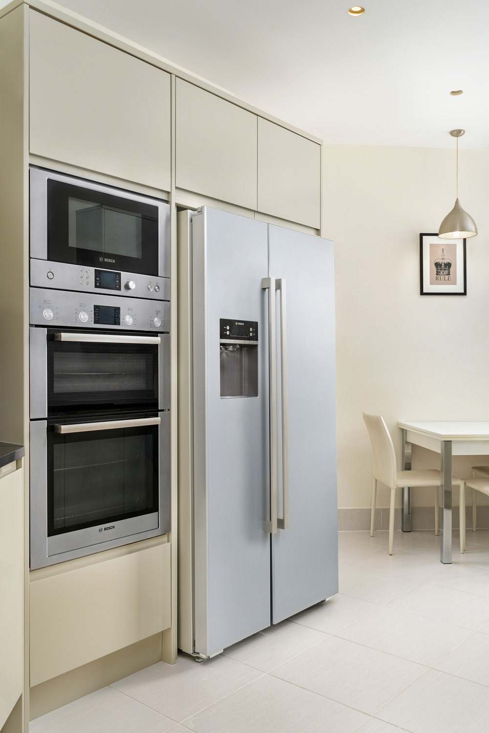 Oven, Microwave and a Fridge in a Pastel Yellow Kitchen with a small dining table in the corner
