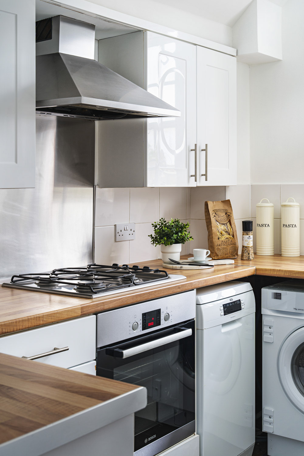 Kitchen photograph showcasing the stove with extractor fan, worktop, dishwasher and a washing machine