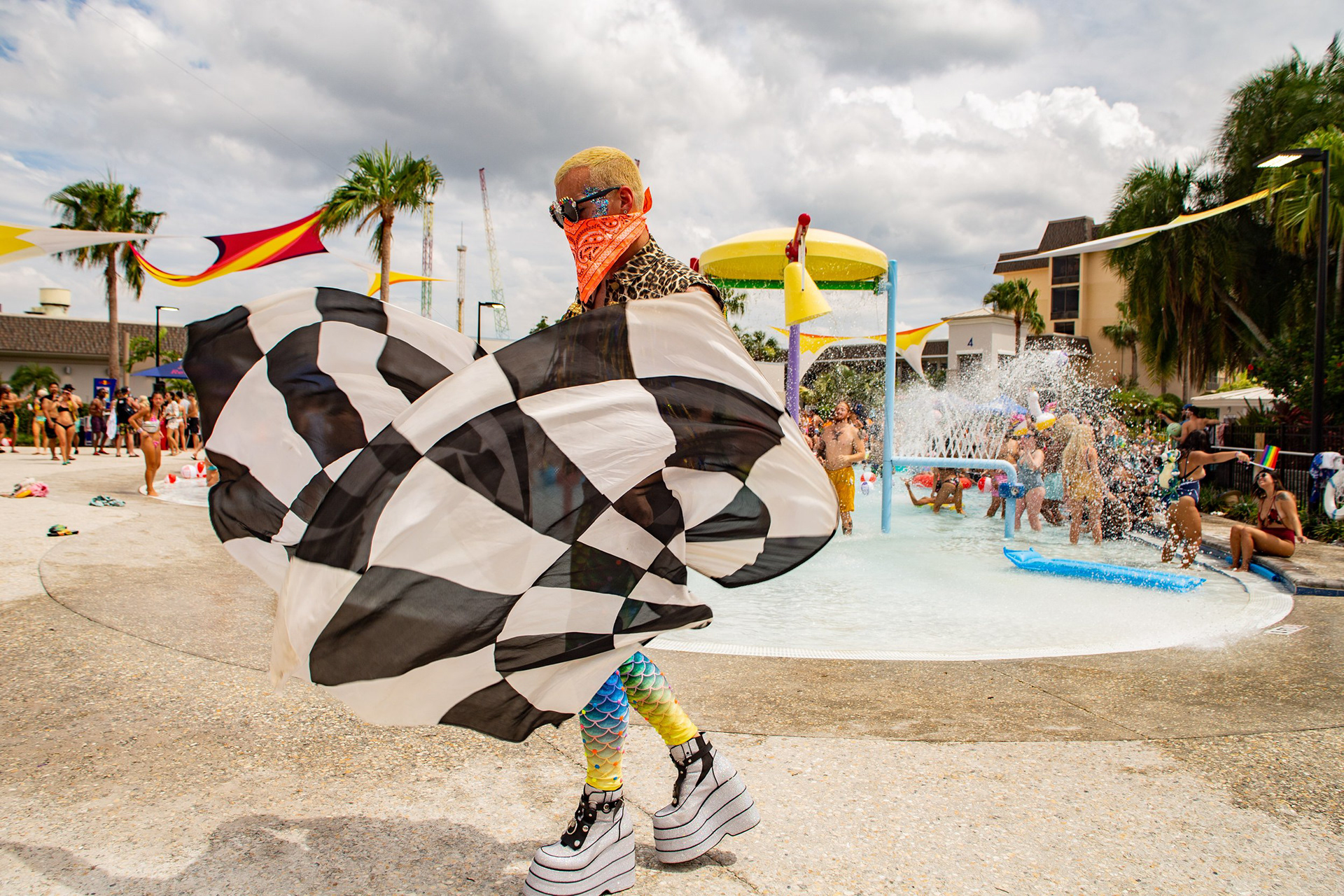 Creative movement at the HomeBass Pool Party. A lifestyle portrait of a festival 'shuffler' utilizing a patterned cape to add a dynamic, decorative element to the resort’s high-energy atmosphere.