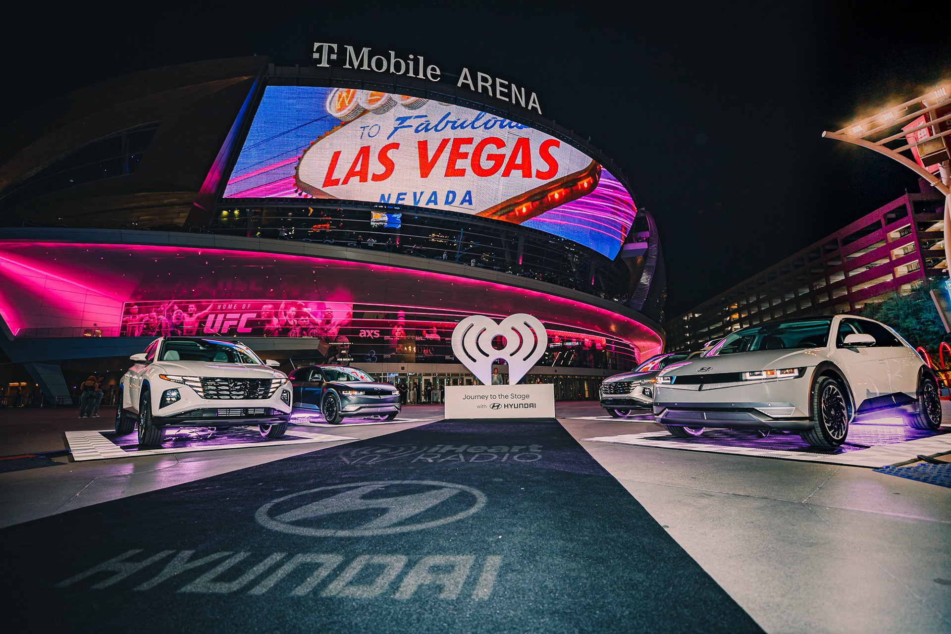 The Hyundai vehicle showcase at the T-Mobile Arena entrance. Evening brand activation featuring 'Welcome to Las Vegas' digital messaging for the iHeartRadio Music Festival.