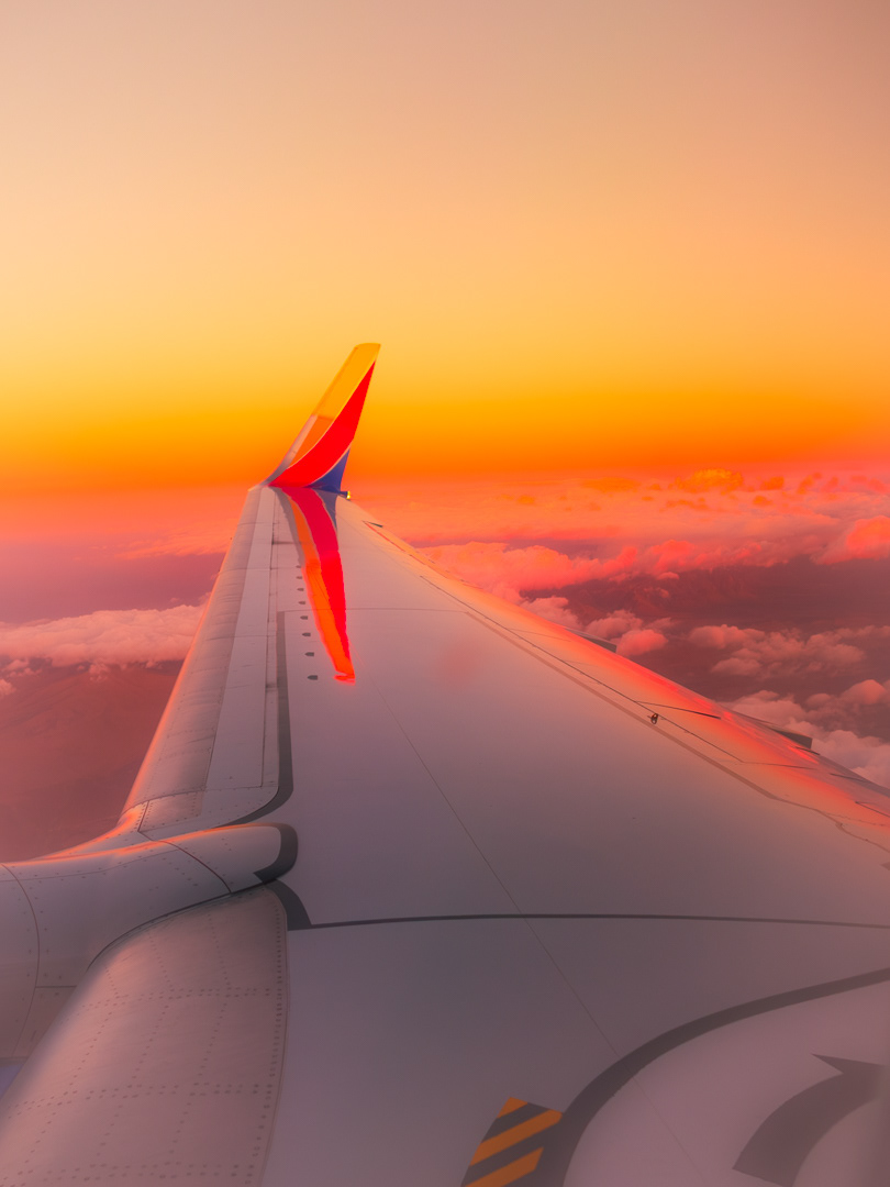 December 2024 - View of a Southwest airplane wing during sunset with colorful sky and clouds below. Photo: Savannah Rowley