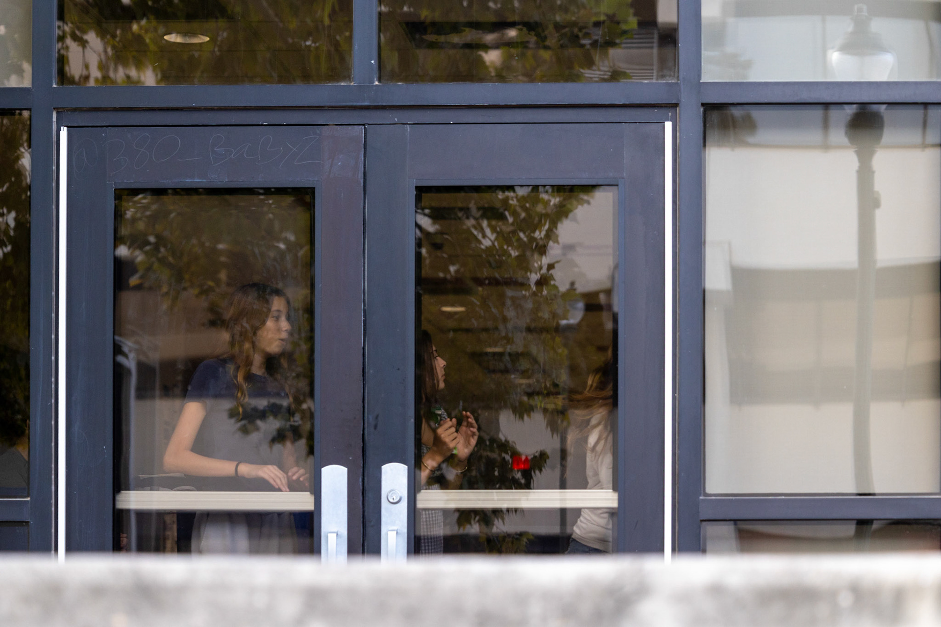 Students at Fox Tech High School look out the school doors as protesters gather outside on Oct. 7, 2025, in San Antonio.