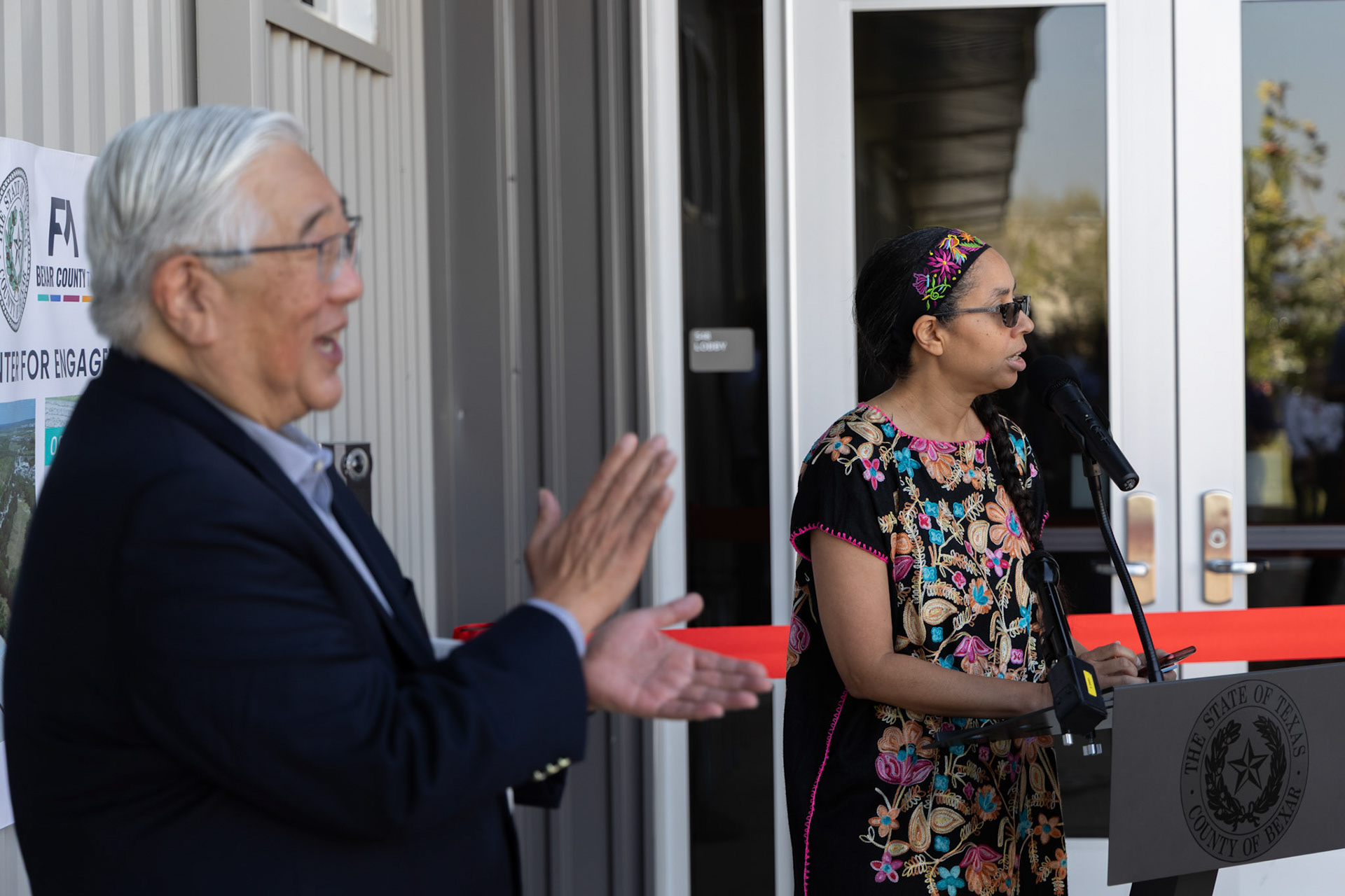 County Judge Peter Sakai claps as Precinct 1 Commissioner Rebeca Clay-Flores speaks at  the opening of the new expansion at the Applewhite Recovery Center on the South Side on Oct. 9, 2025, in San Antonio.
