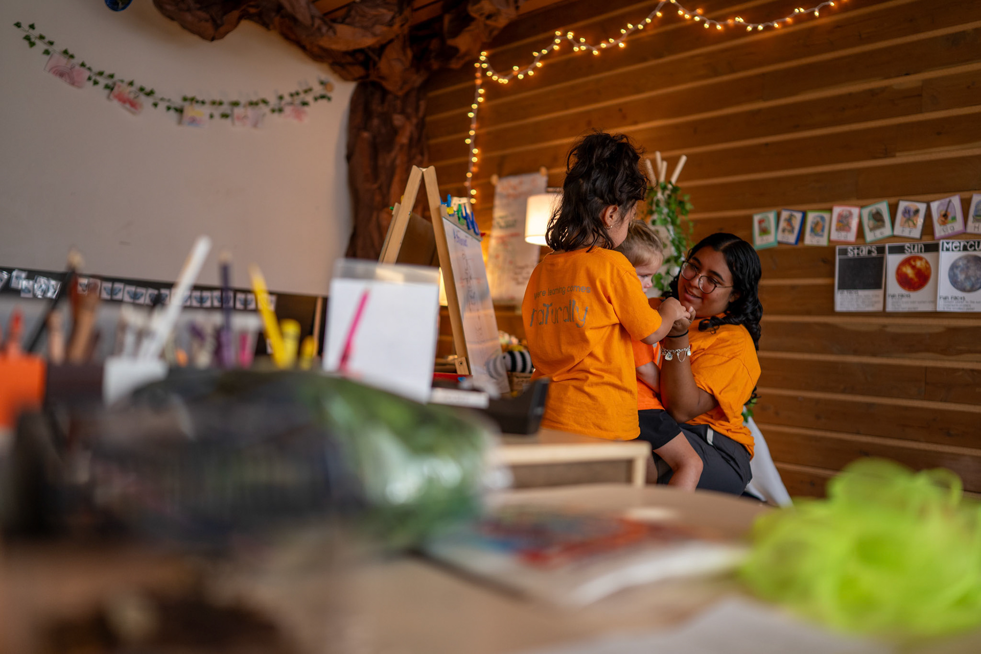 Lead teacher Kat Flores holds a child in her lap while interacting with another in a classroom at the Will Smith Zoo School in San Antonio on June 17, 2025.