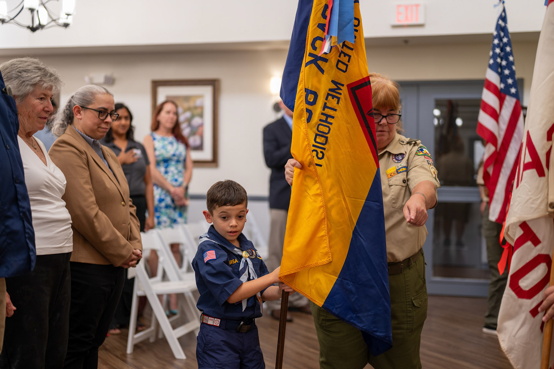 A child and his Boy Scouts of America Troop leader present the colors at the Valor Hills Apartments opening ceremony July 29, 2025.