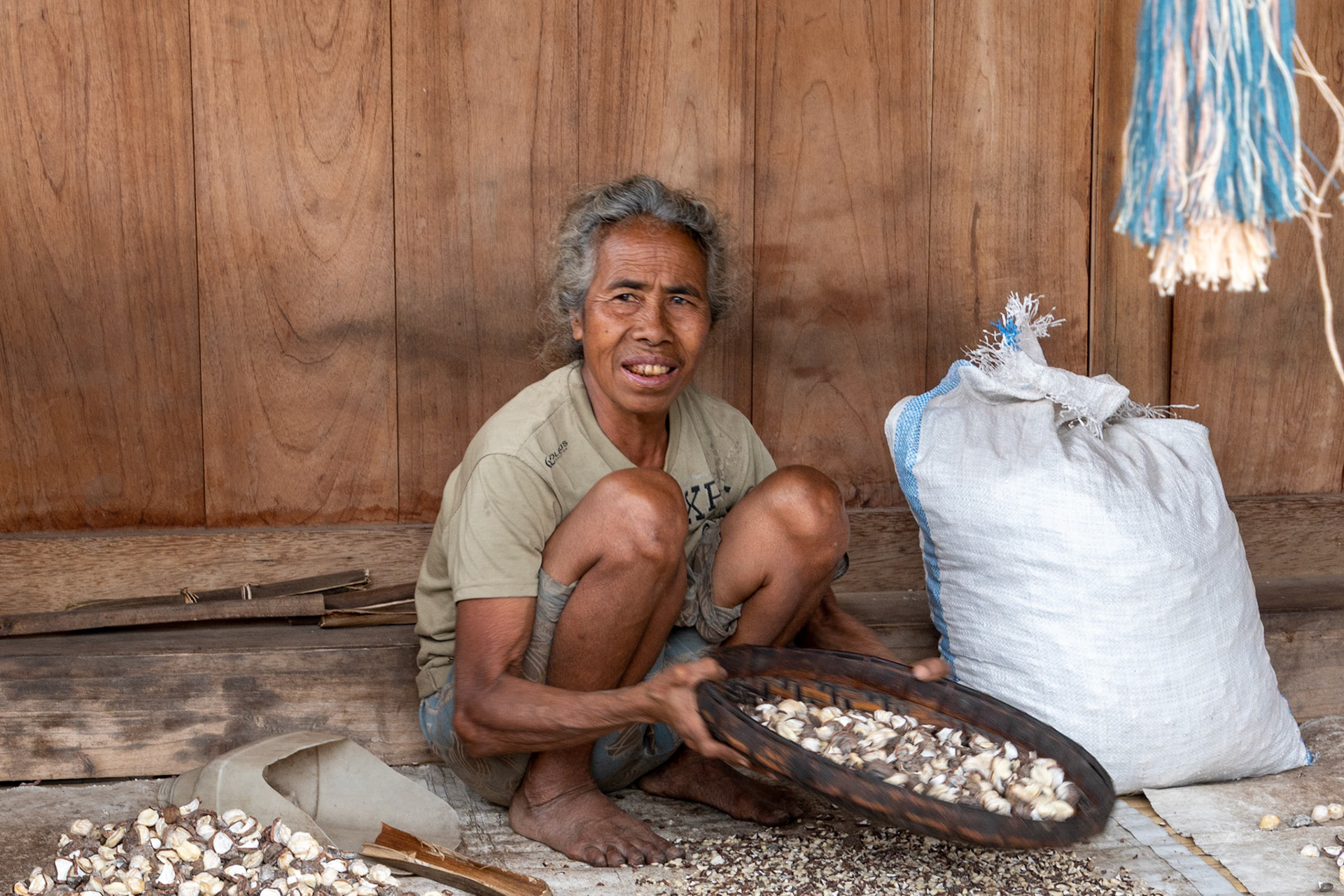 Elderly lady sorting candle nuts, Bena Village, Indonesia