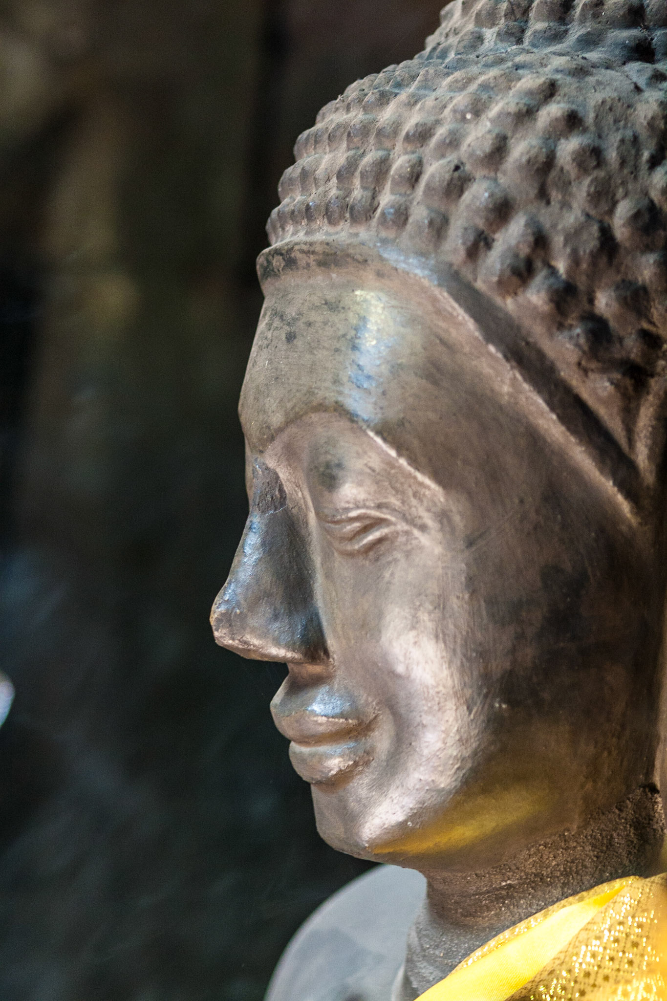 A Buddha statue with a yellow scarf inside the ruins of Banteay Kdei temple in Angkor