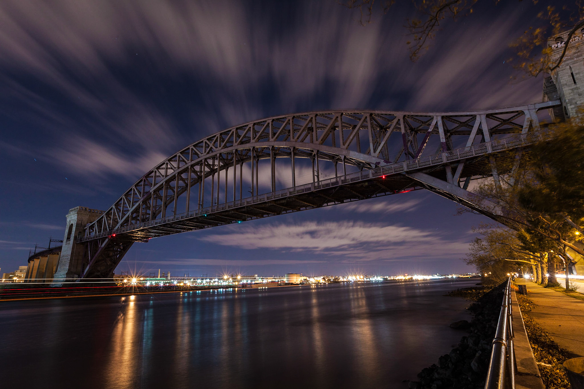 A night photography of Hell Gate Bridge (train bridge), seen from Astoria Park in Queens, New York City. Clouds moving fast over the bridge in this two-minute exposure.