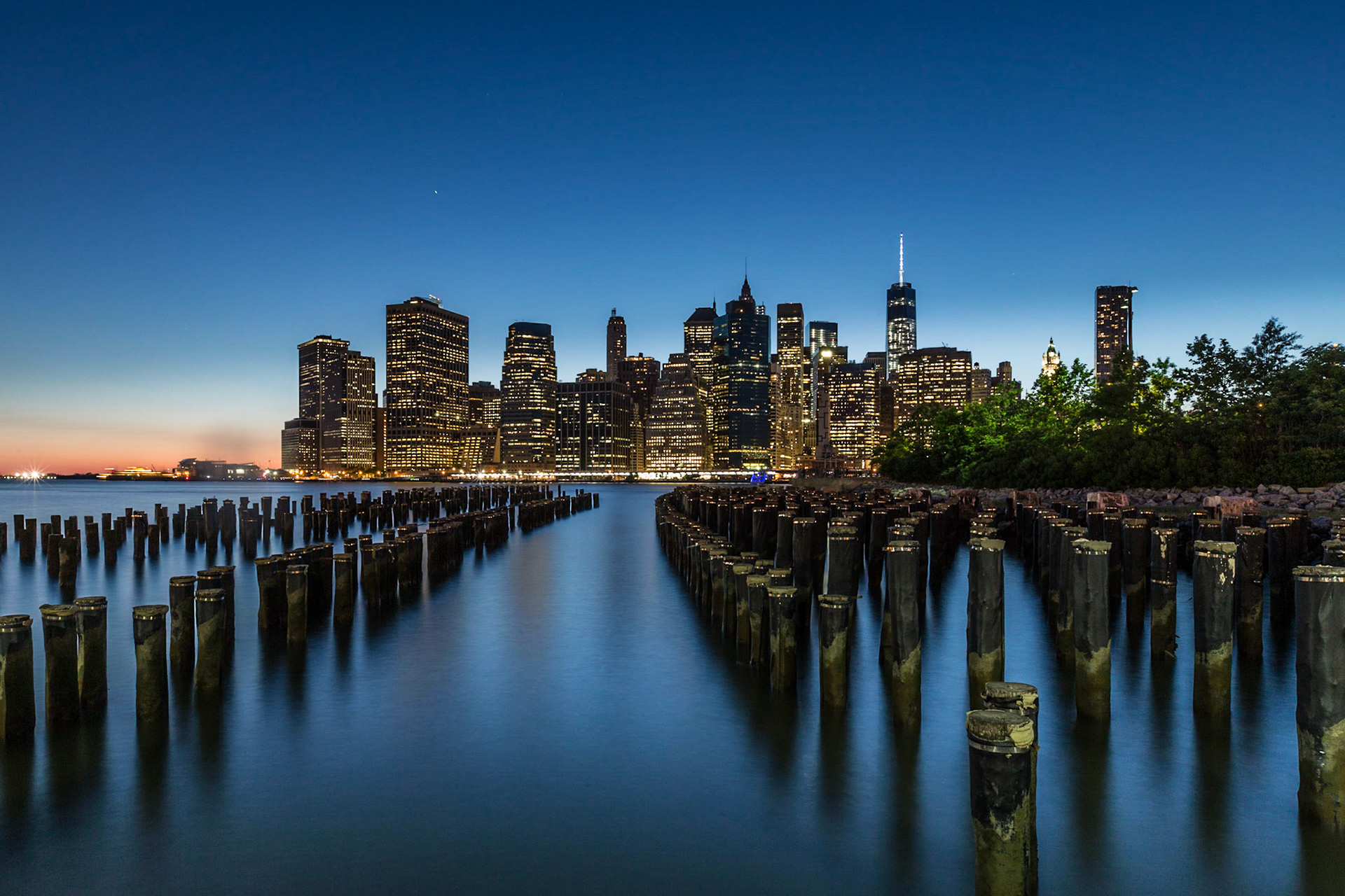 View over a polefield of an old pier towards the Downtown Manhattan Skyline