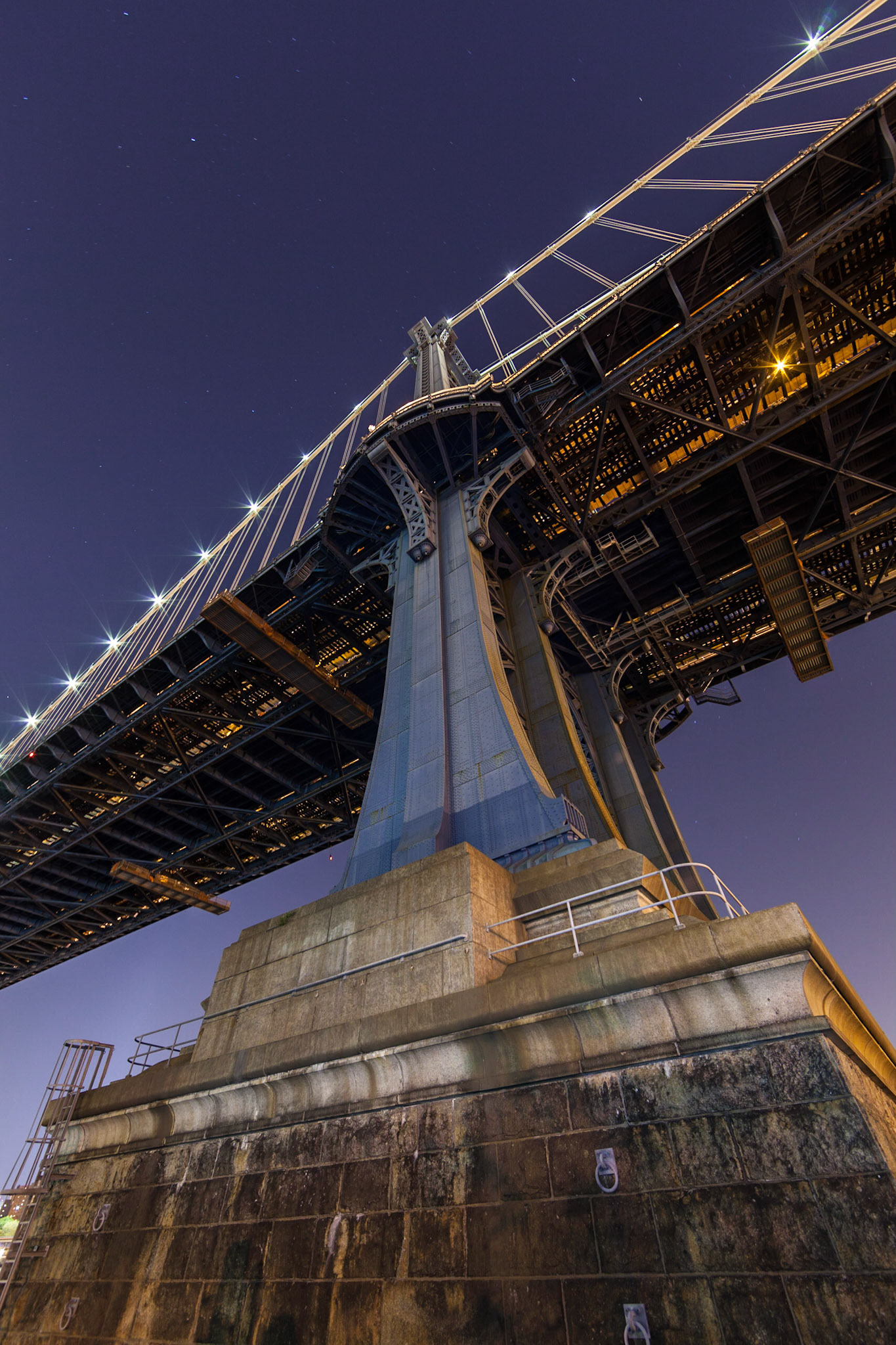 A night photography image of a pylon of the Manhattan Bridge shot from right under the bridge on the Brooklyn side