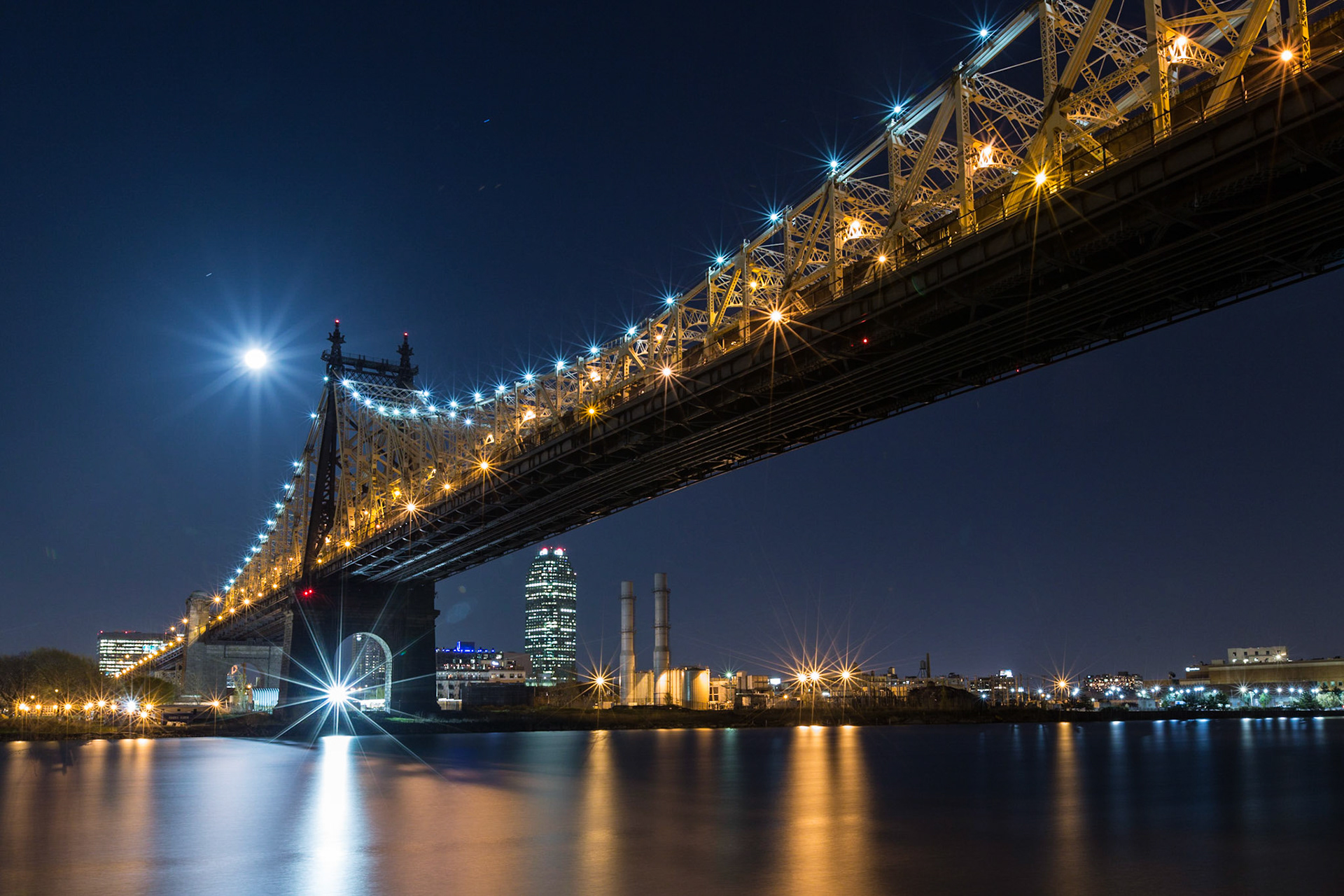The Queensboro Bridge towards Queens from Roosevelt Island at night with the rising full moon