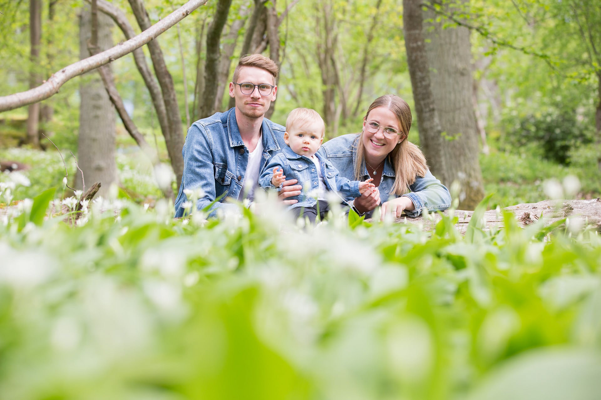 En familj sitter mitt i skogen med sin bebis