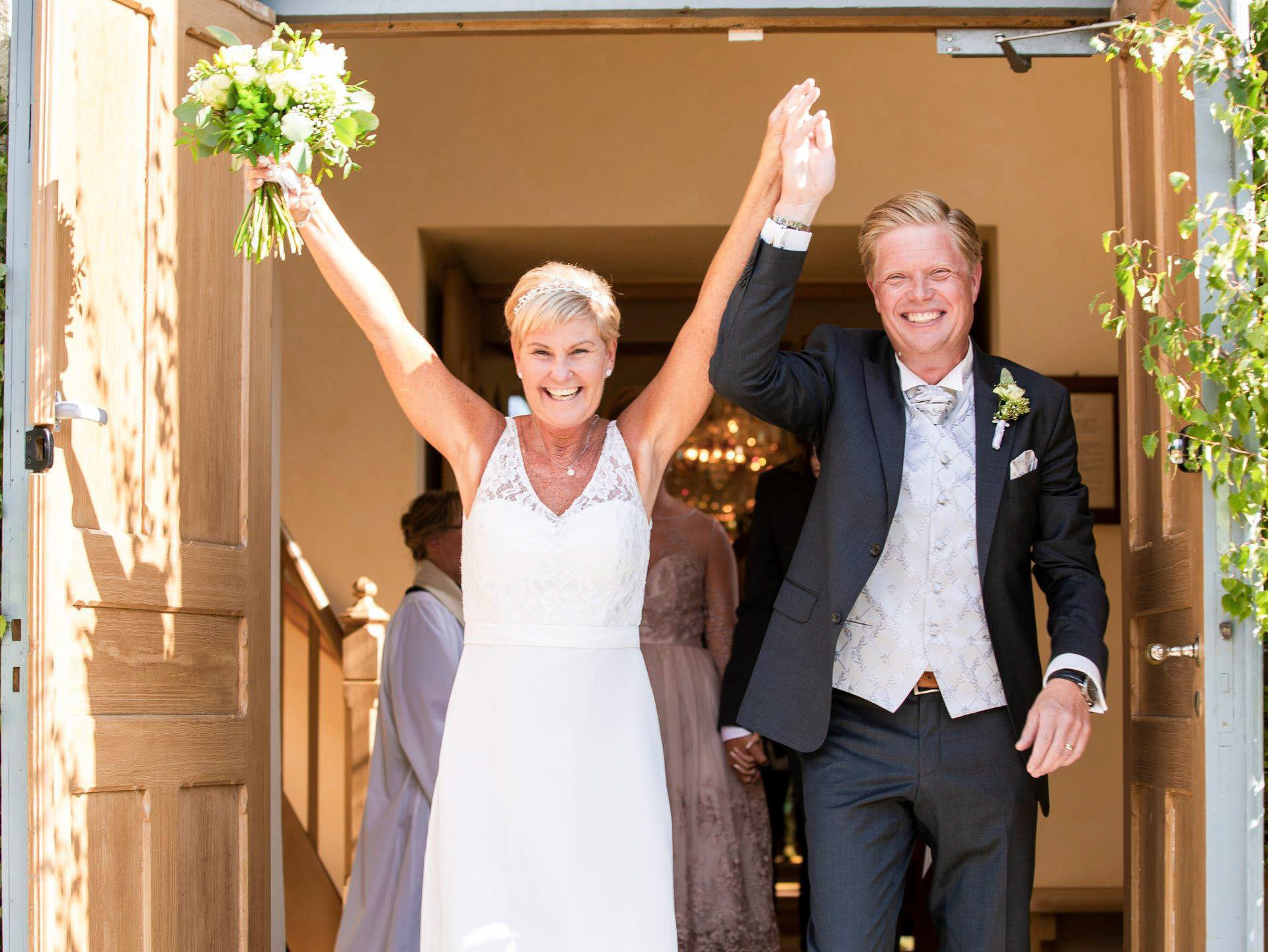 Nygift par kommer ut från kyrkan med händerna i luften