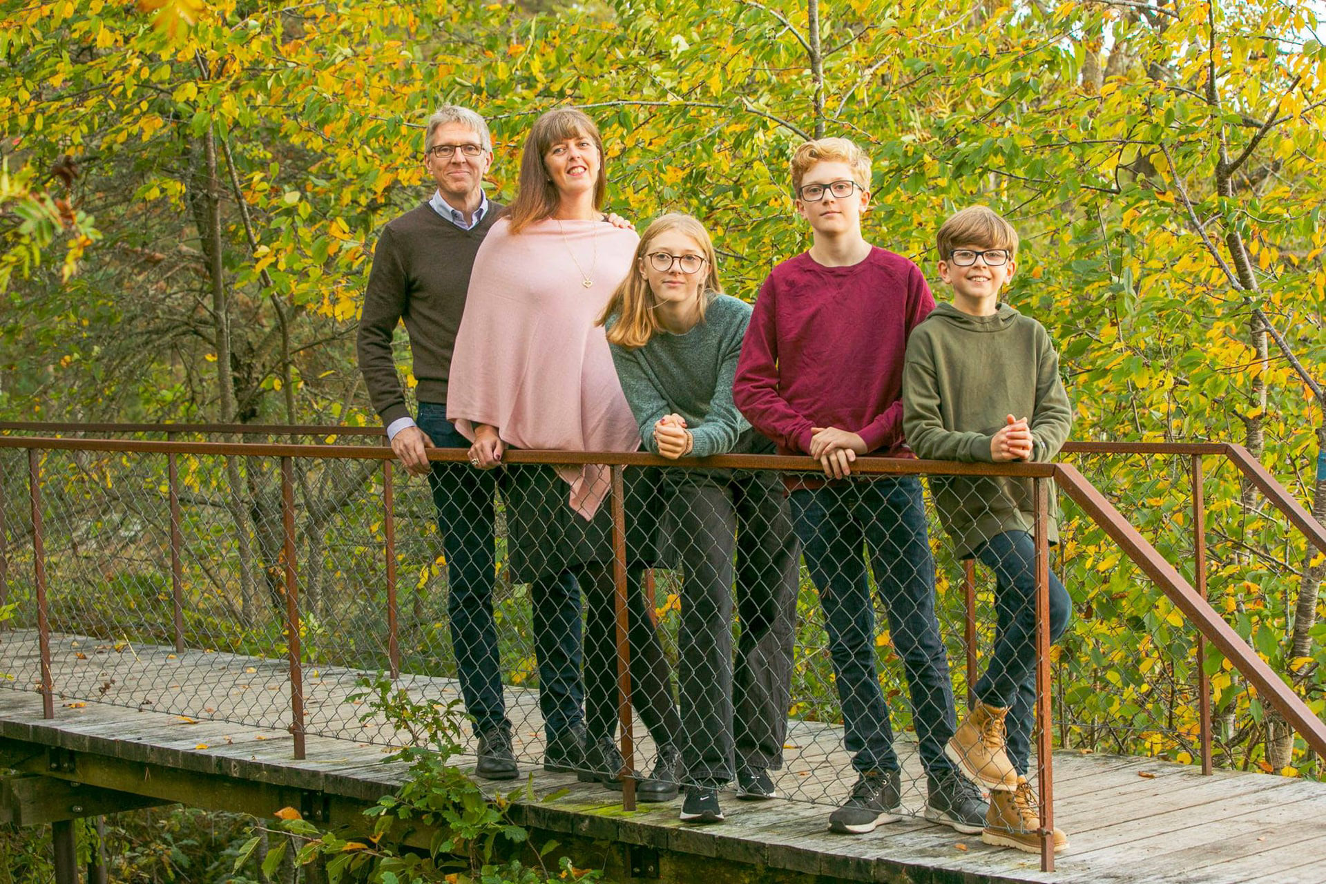 En familj står på en bro i skogen