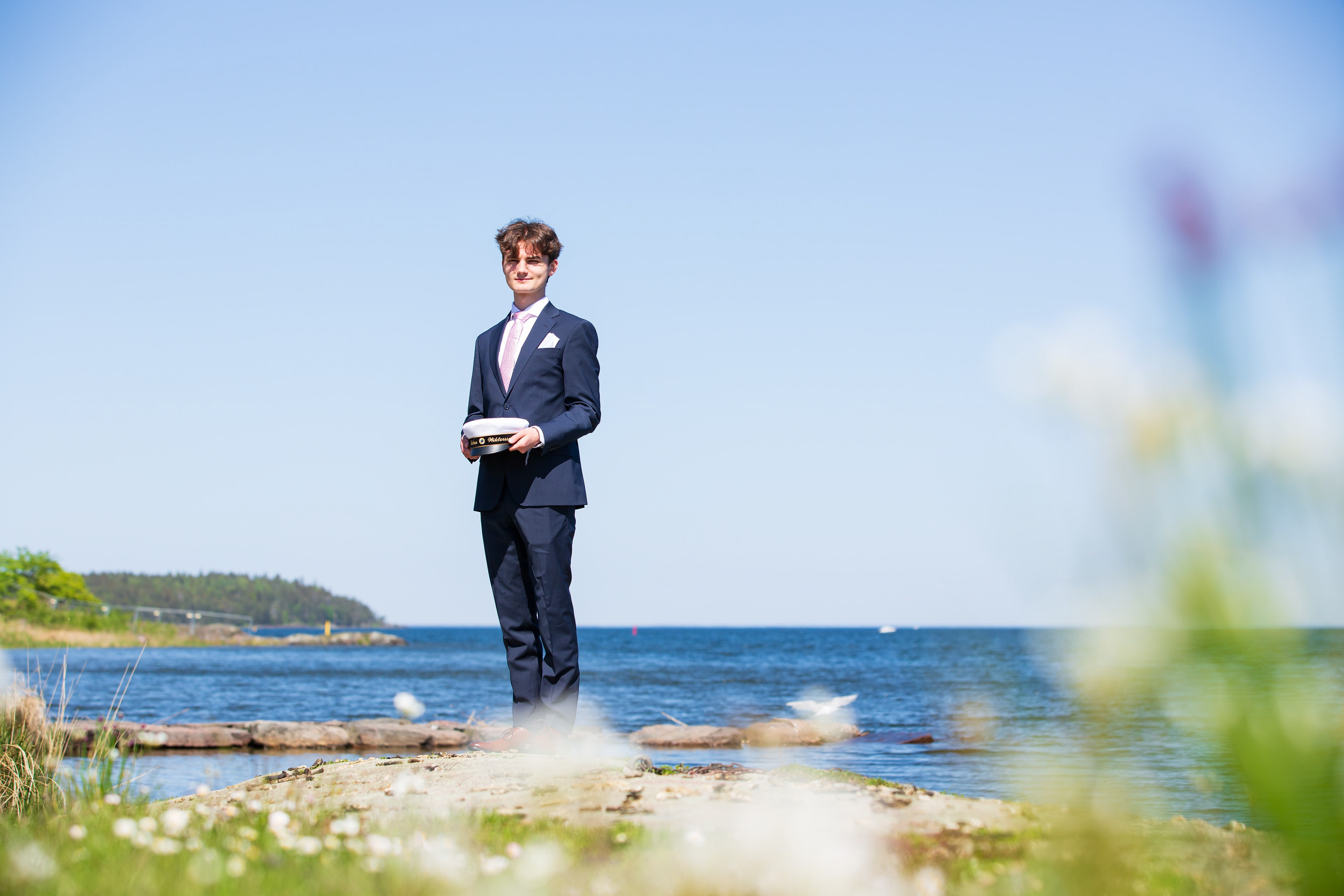 En student visar upp sin mössa vid sjön